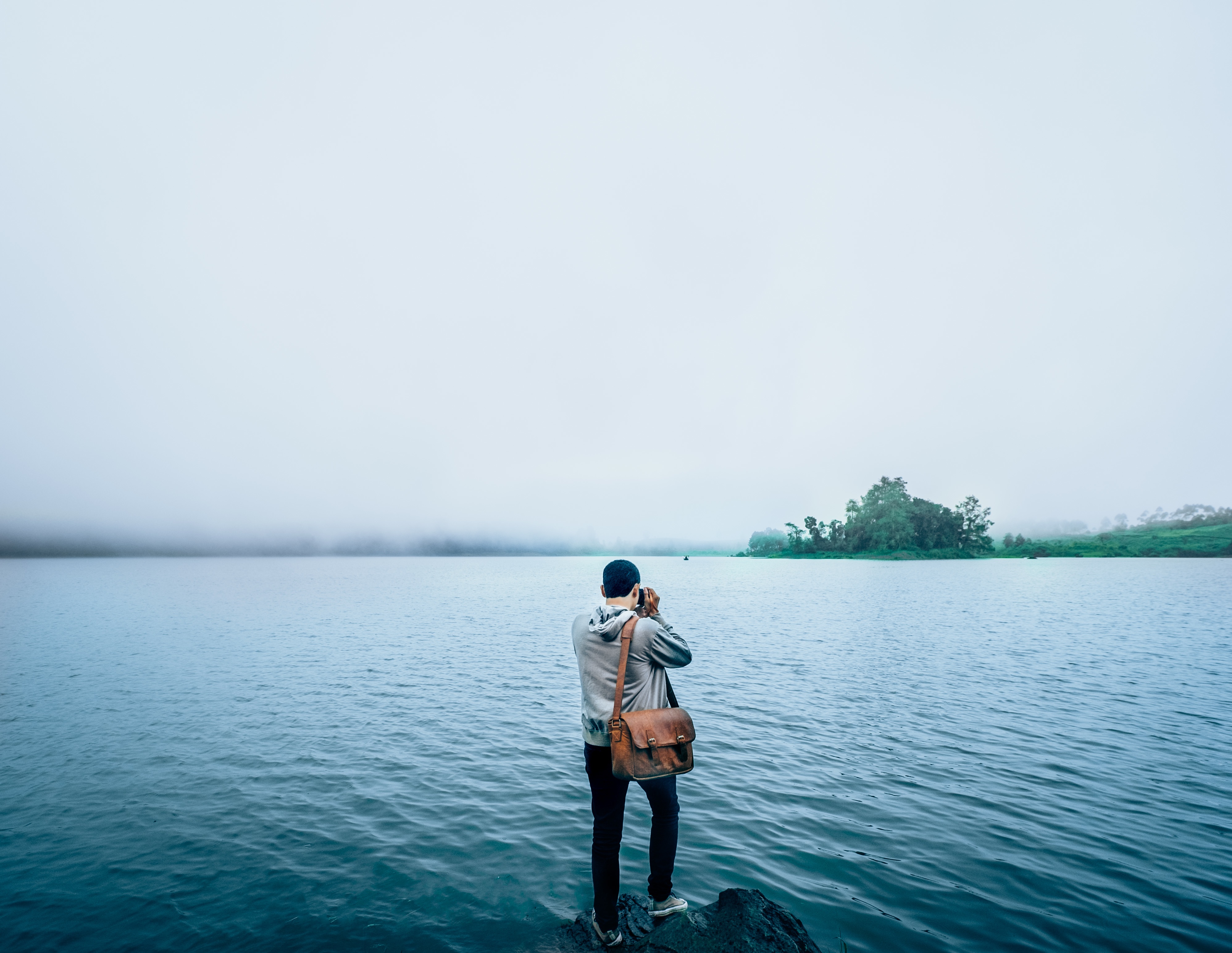 免费照片一名男子拍摄晨雾中的湖面