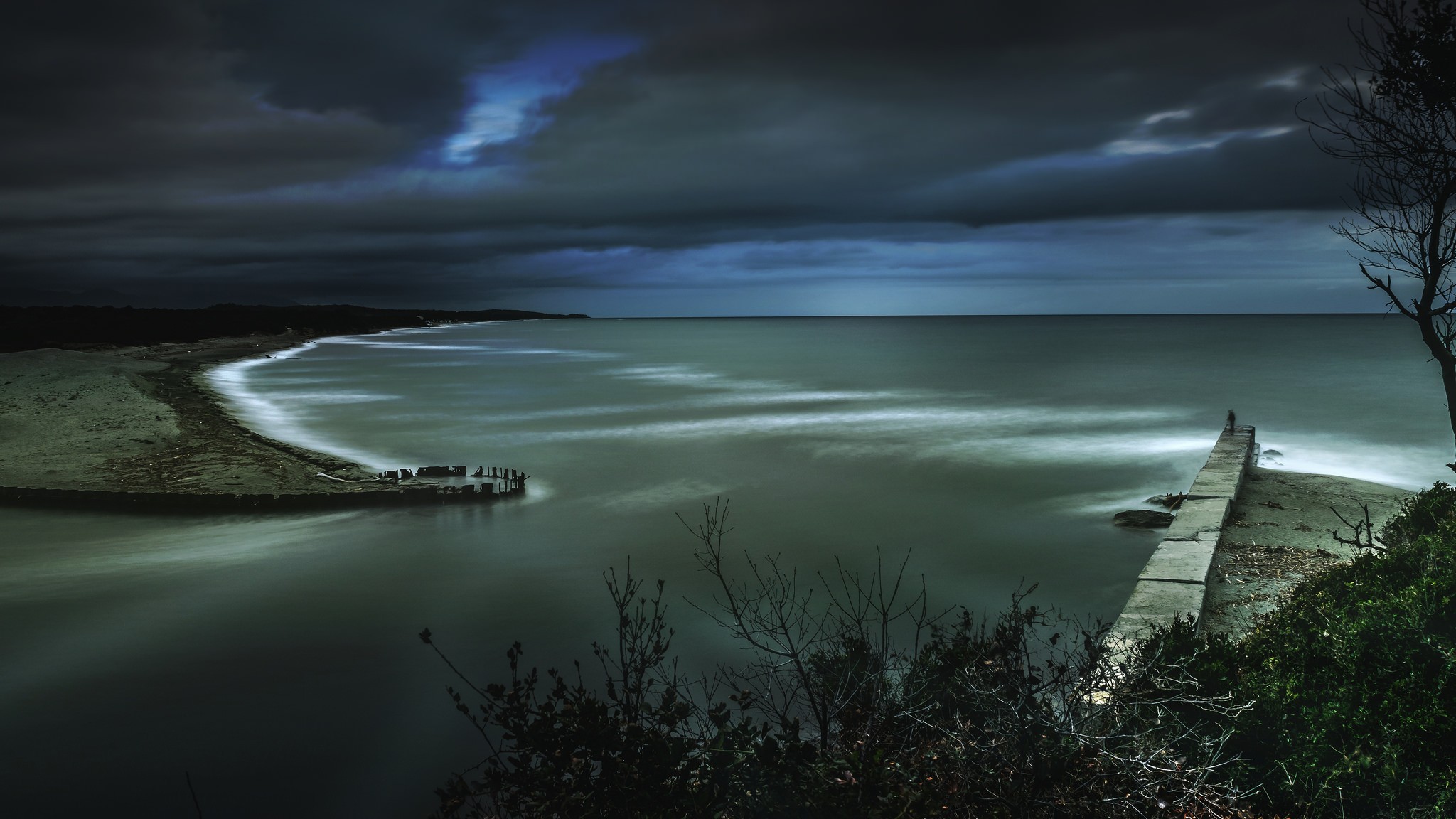 Бесплатное фото Морской пейзаж с пирсом, освещенной водой и облаками на небе.