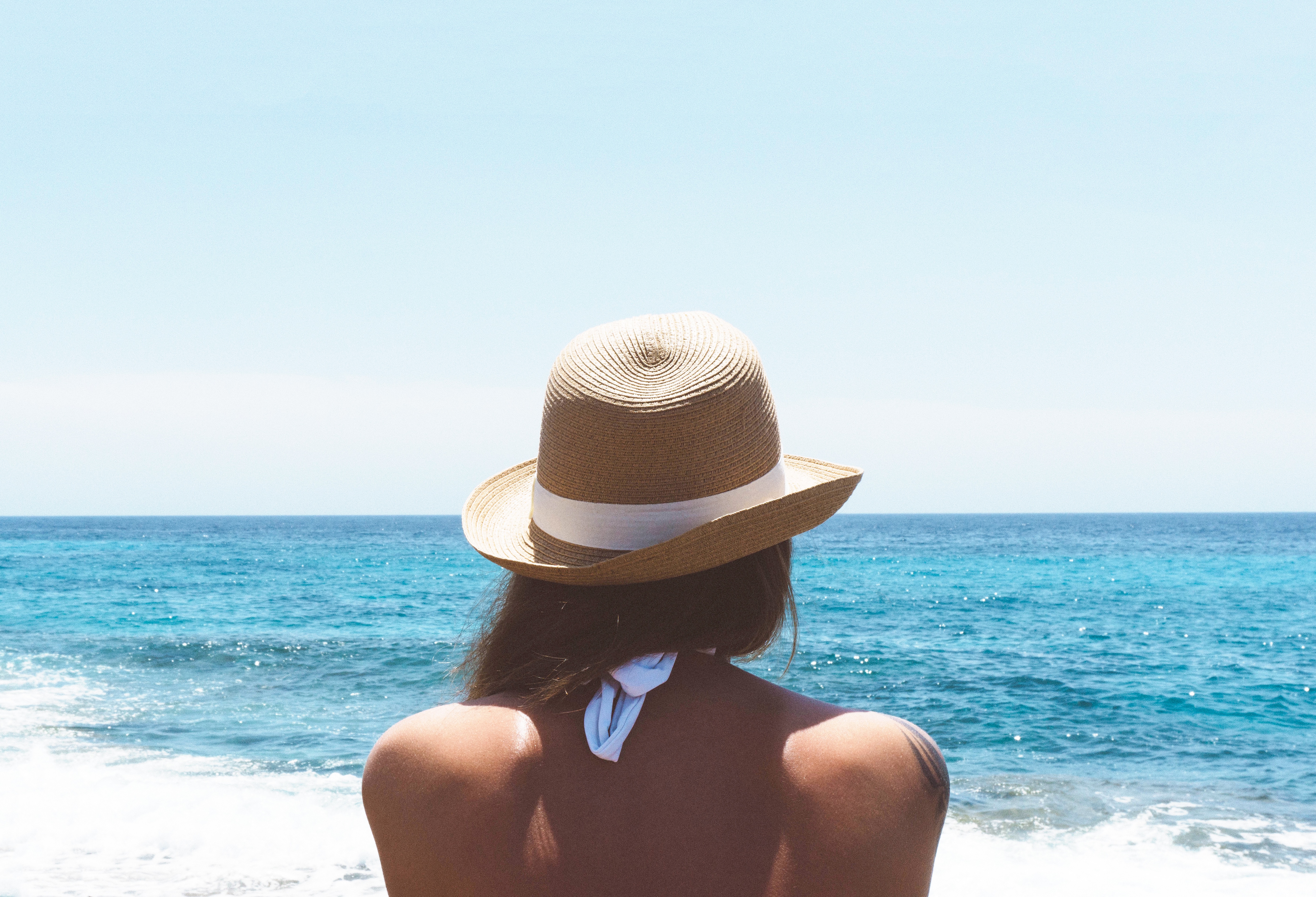 Free photo A woman in a hat looks out to sea