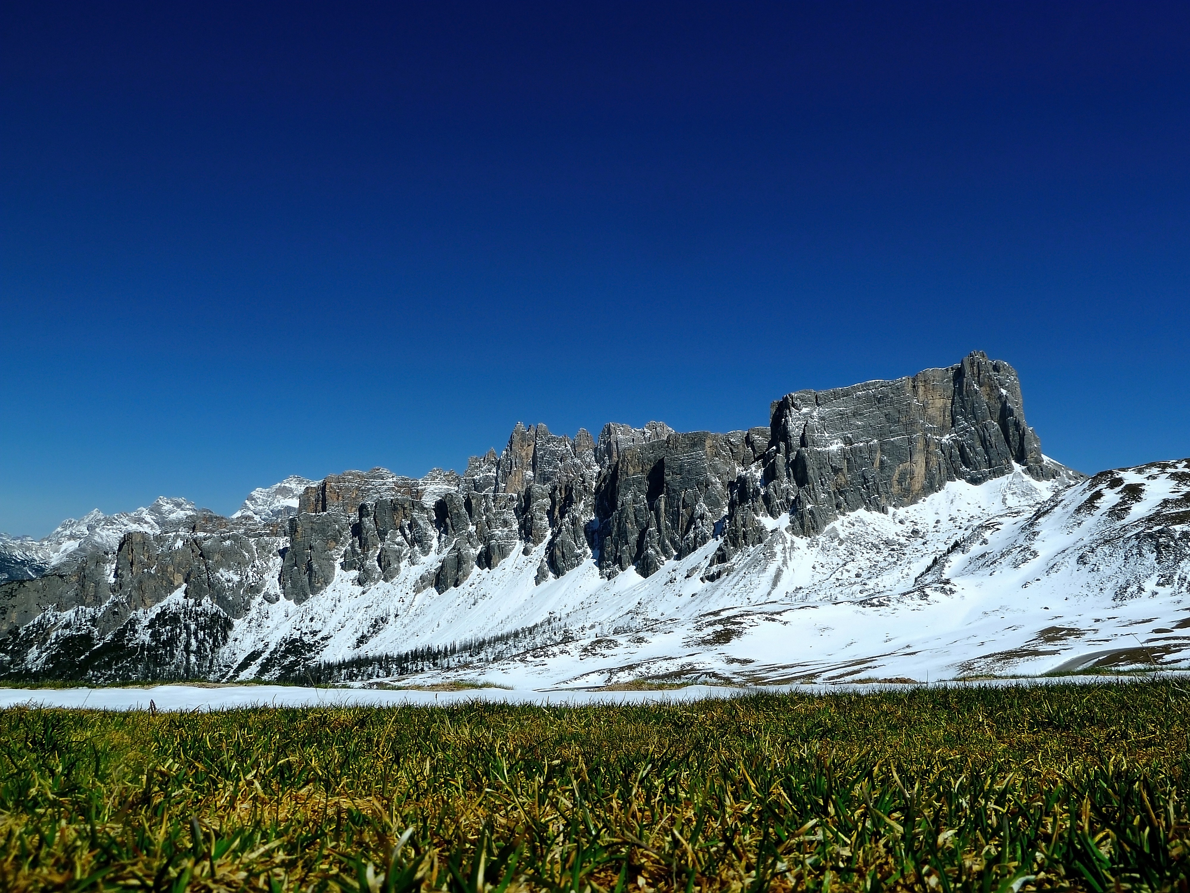 Free photo Mountains in snow near a field of green grass.