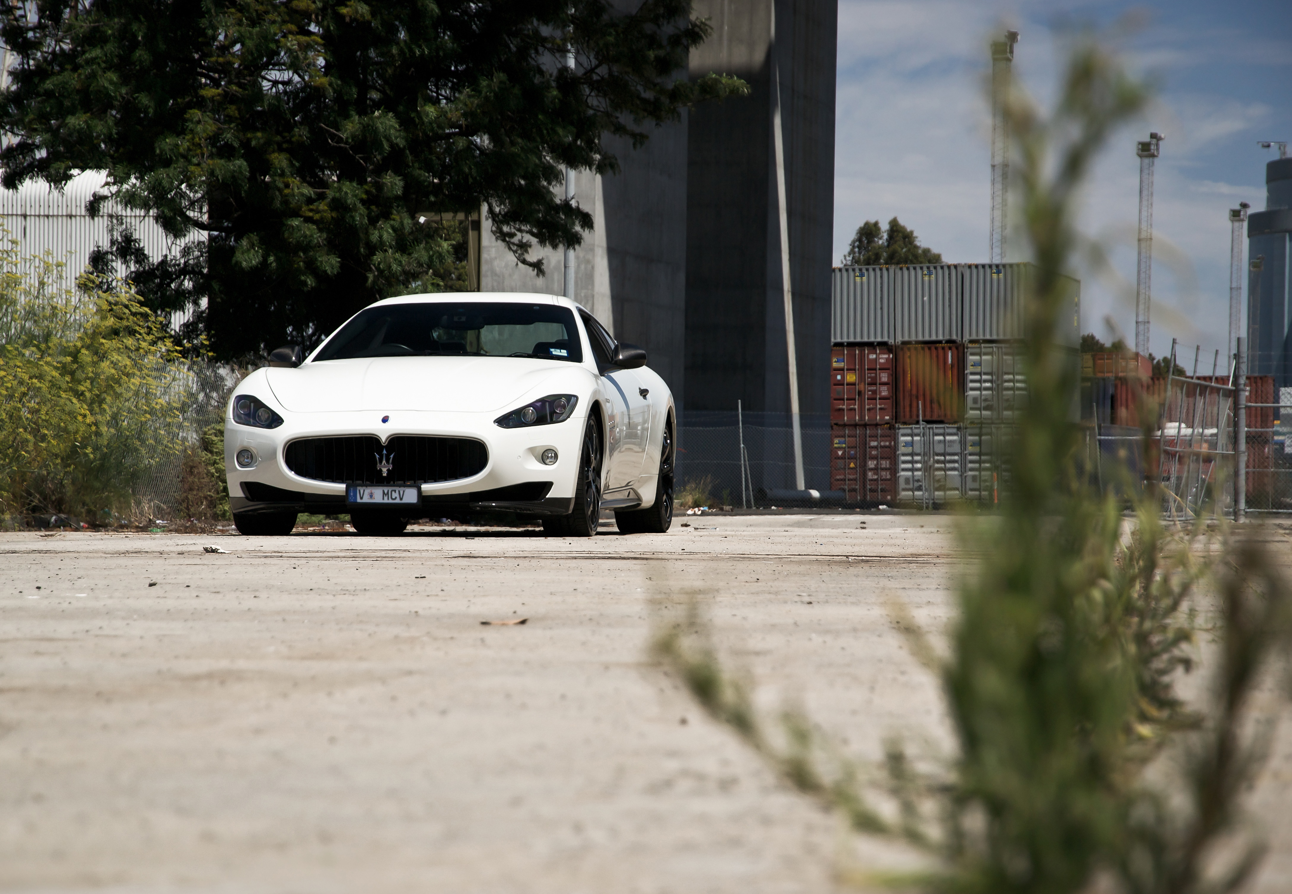 Free photo A white car is driving near the containers