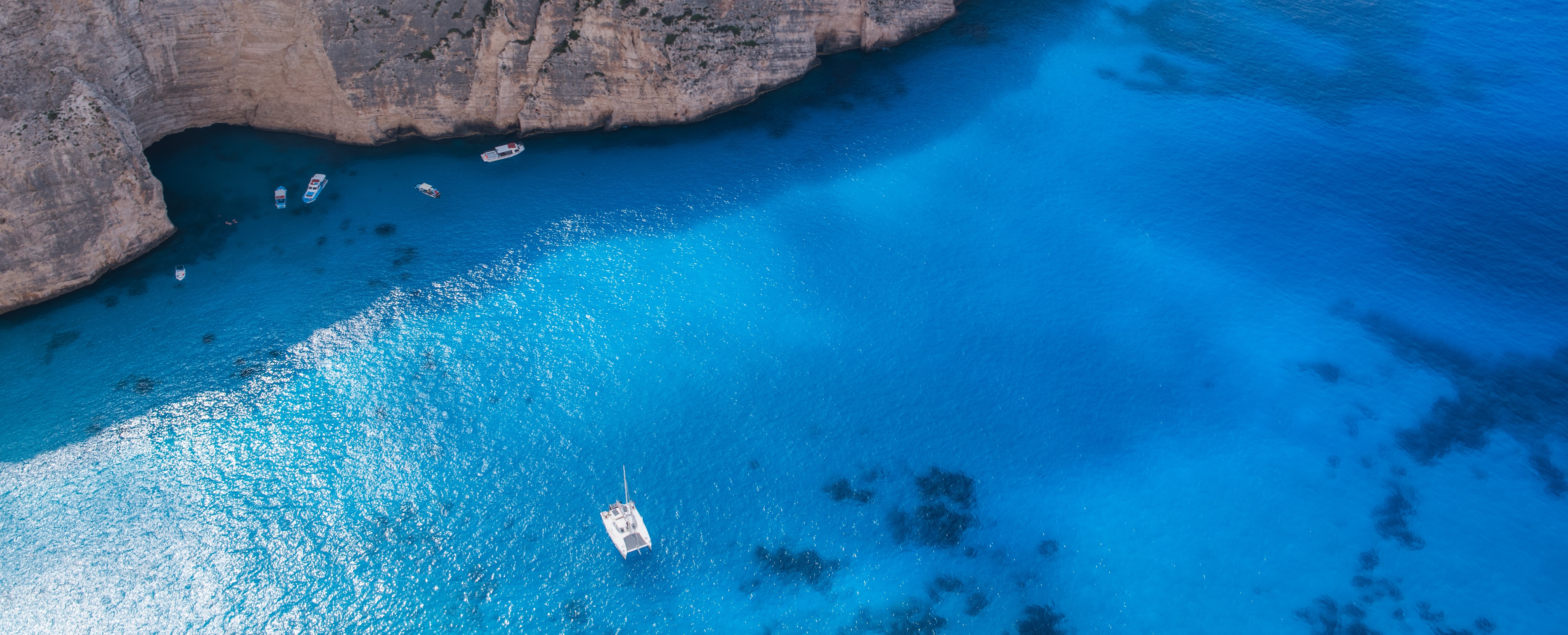 A picture of a lonely sailboat in a blue lagoon.