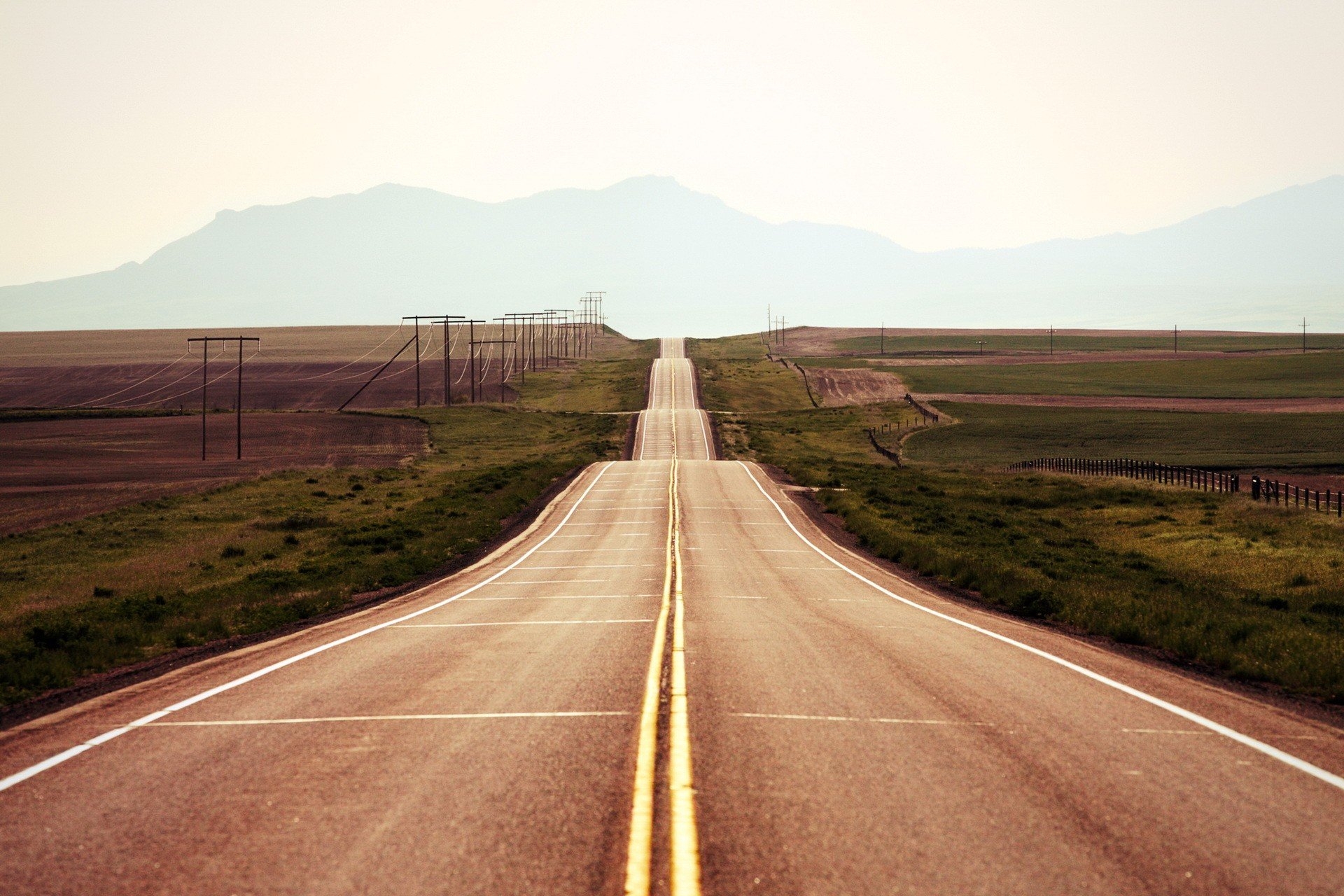 Wallpapers a long road grass mountains on the desktop