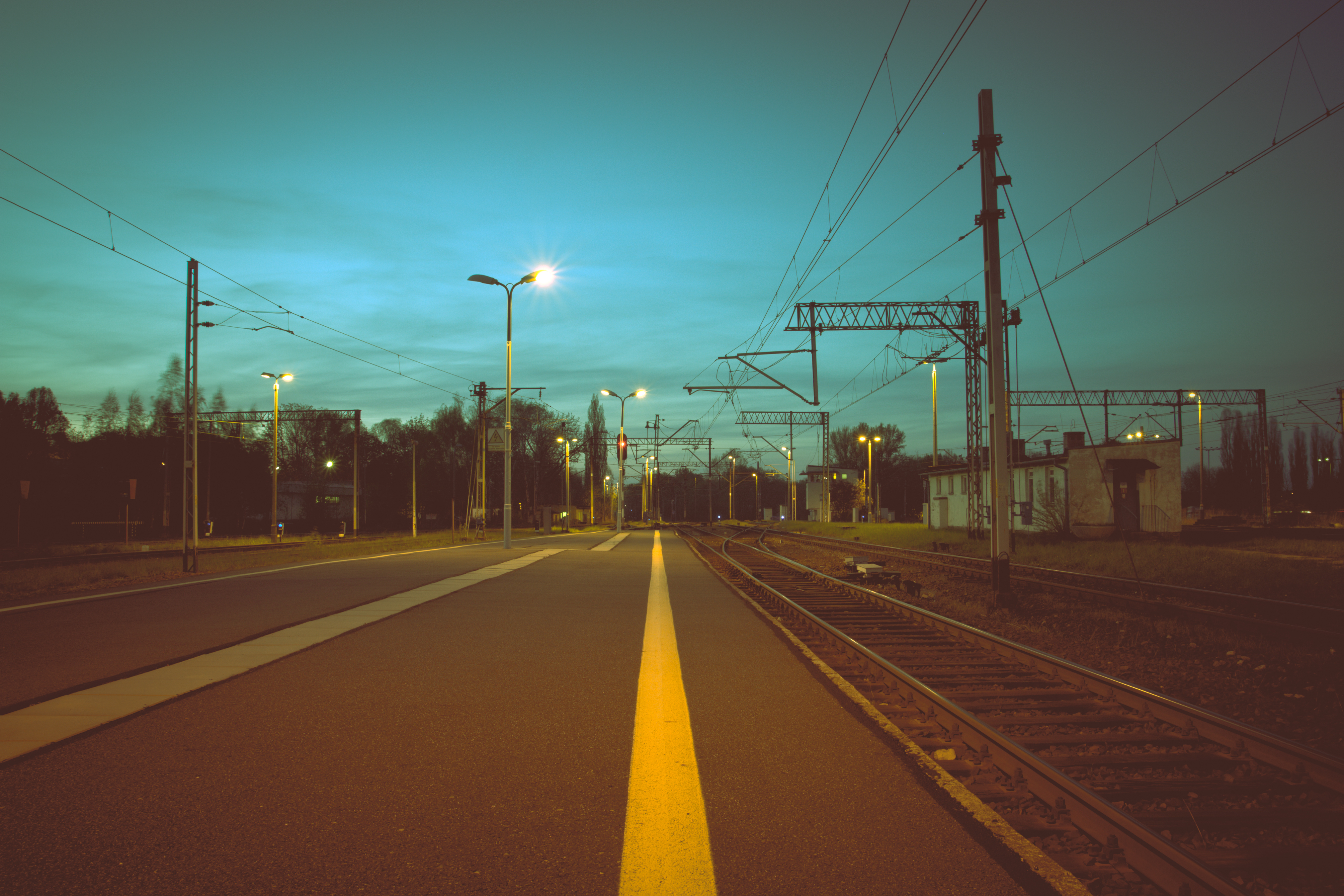 Free photo The night road next to the railroad tracks