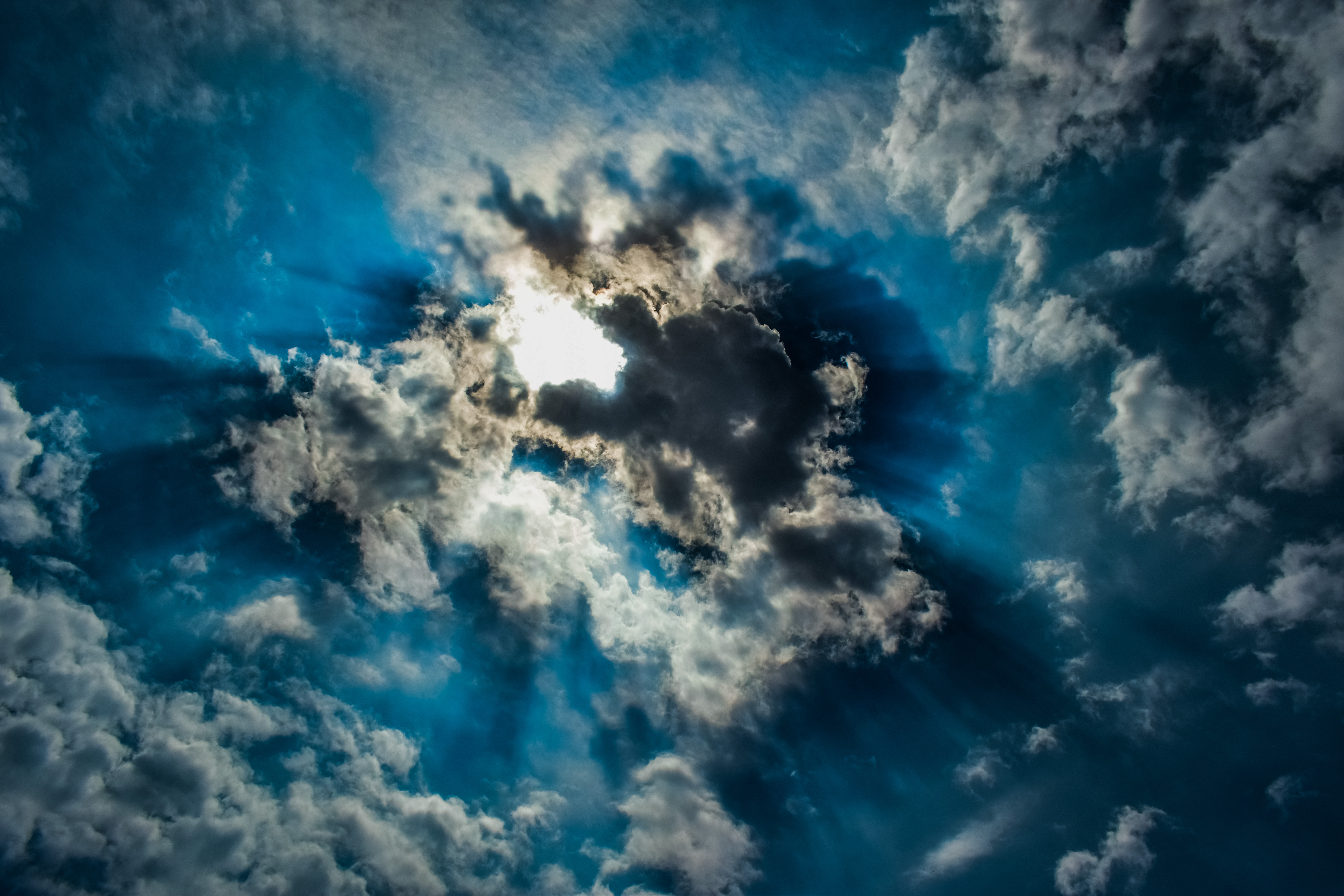 Blue sky with clouds through which the sun`s rays break through