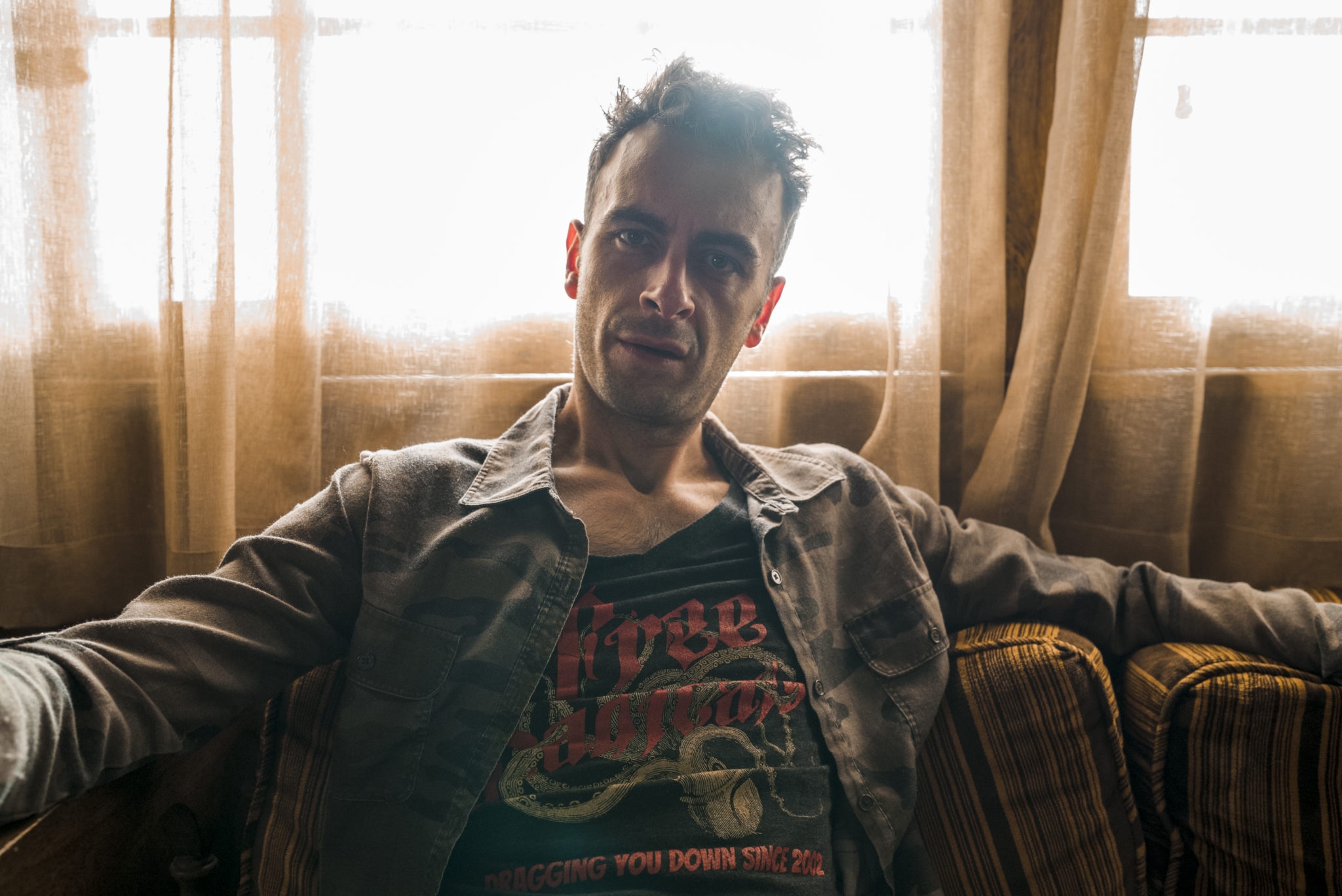 Free photo Actor Joe Gilgan sits on a couch near a window