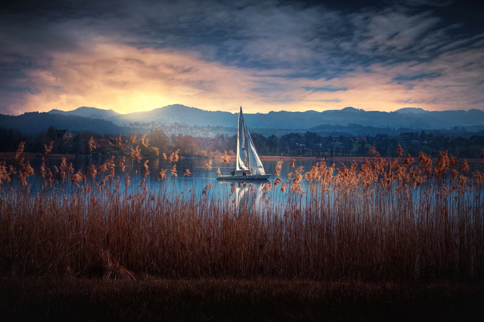 A lone sailboat on the lake during sunset