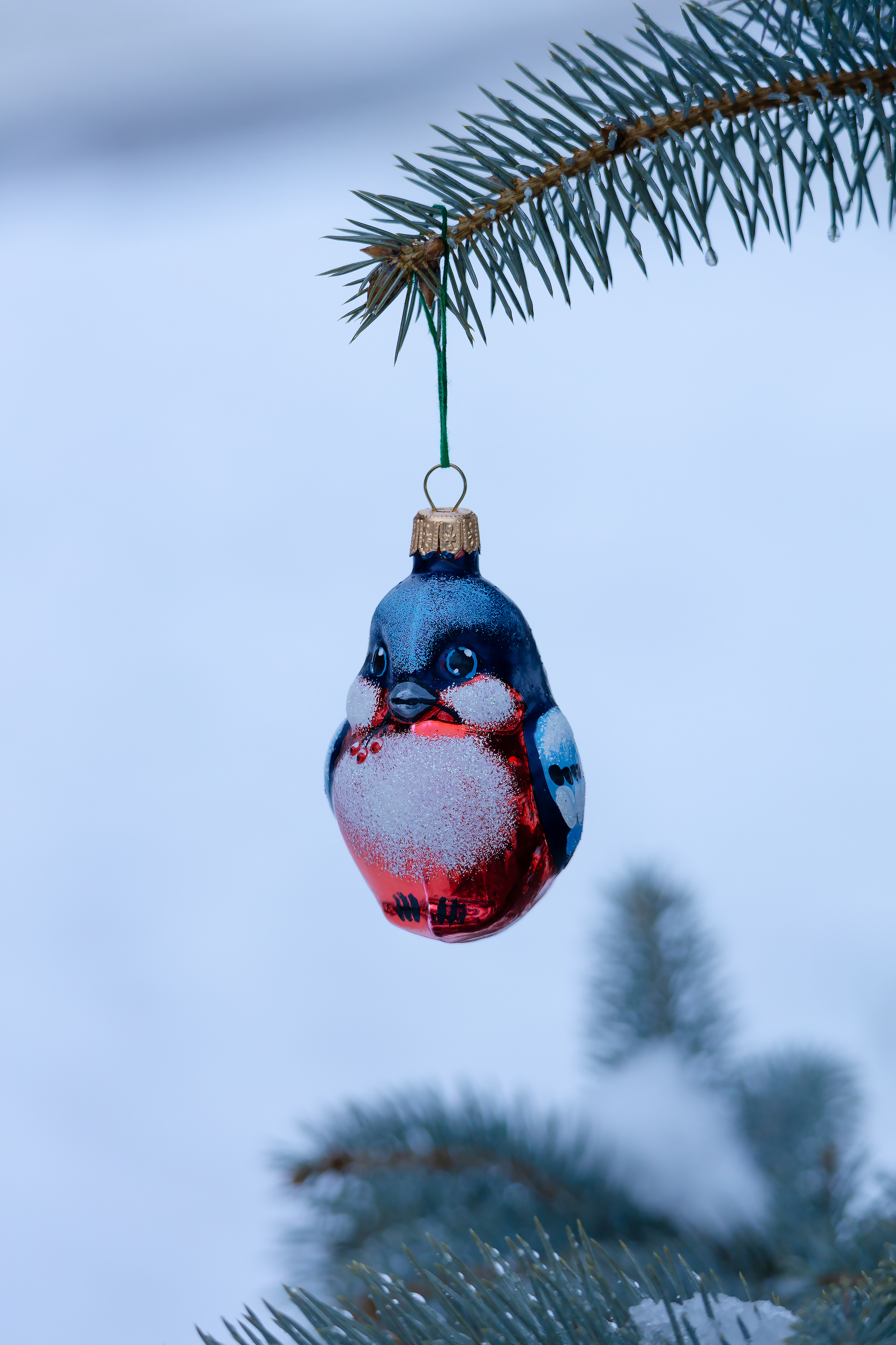 Новогодняя игрушка в виде снегиря на ветке ёлки