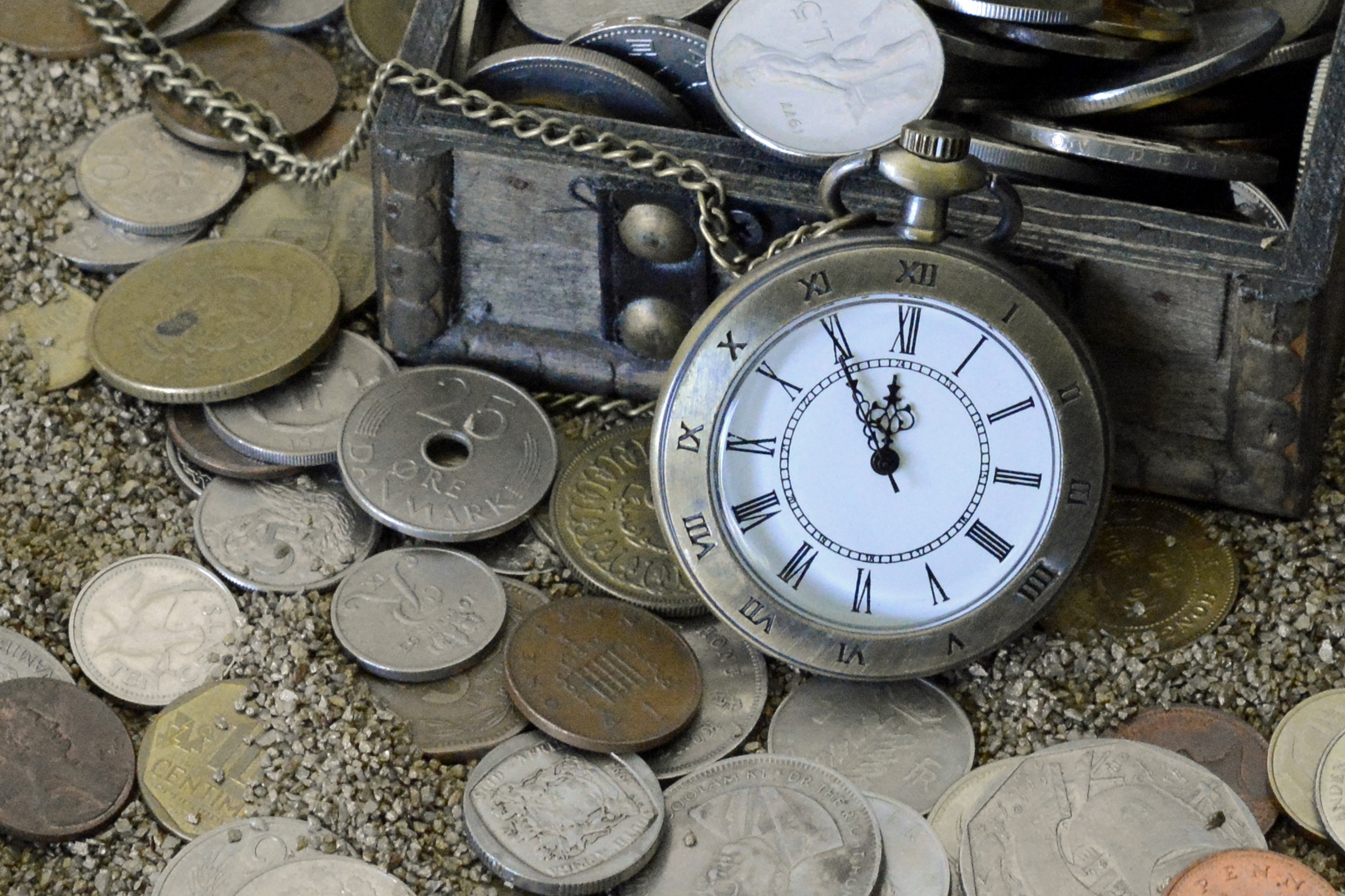 Бесплатное фото Карманные часы с монетами на песке
