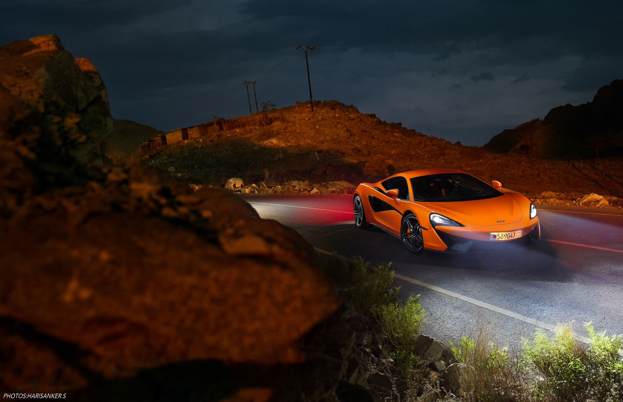 An orange-colored Mclaren on the road at night.