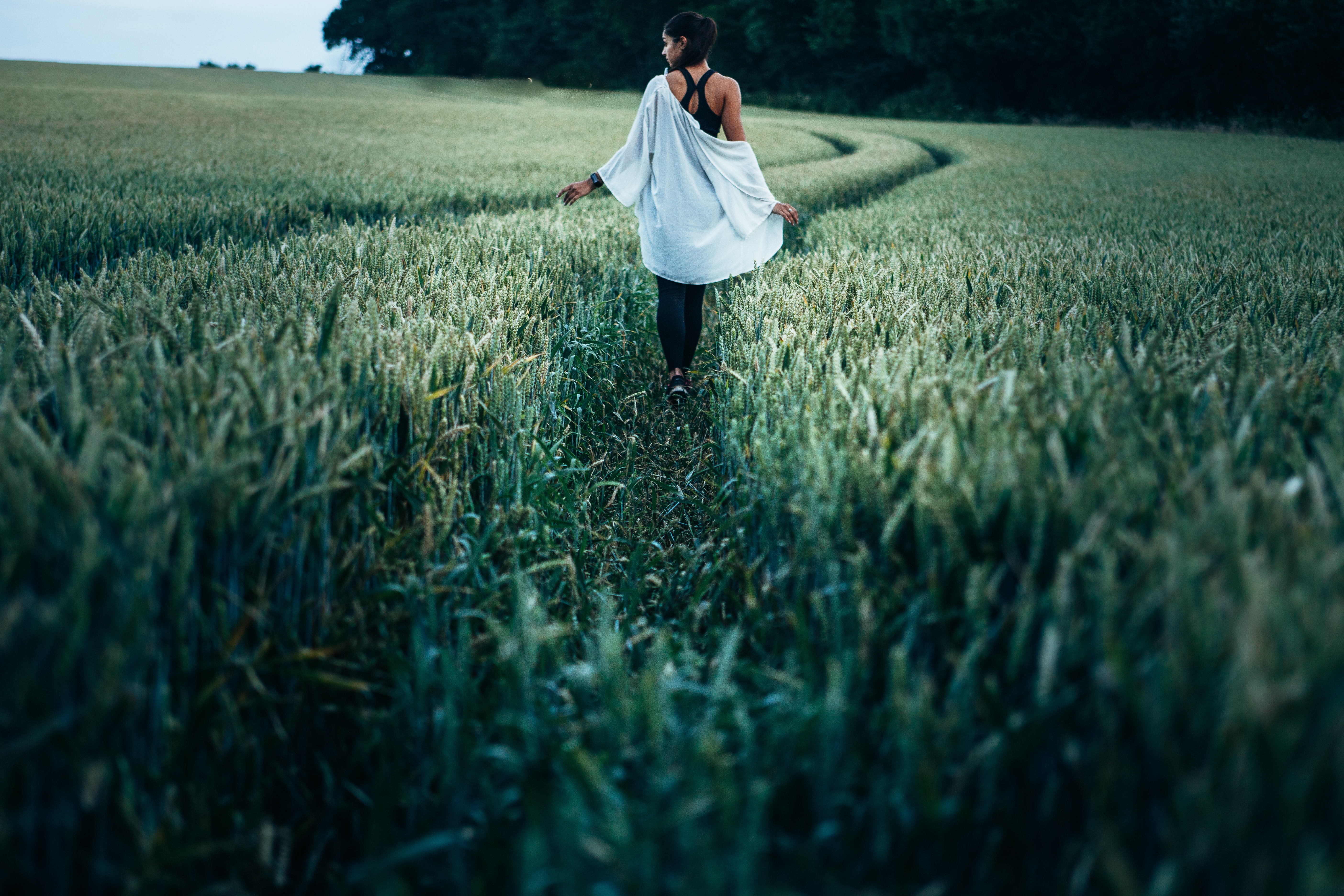 一个女孩走在高高的草地上。