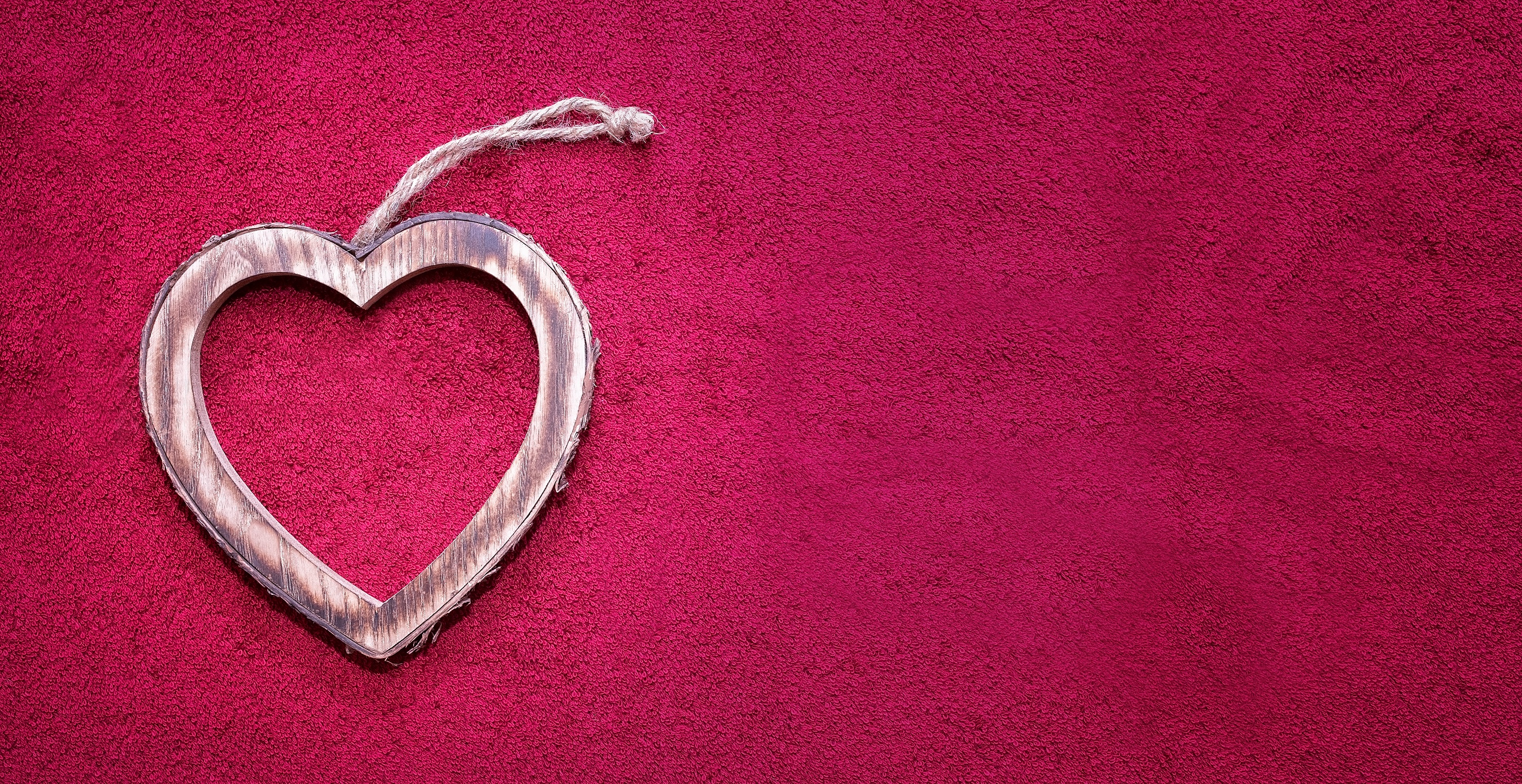 Free photo Wooden keychain in the shape of a heart on a pink background