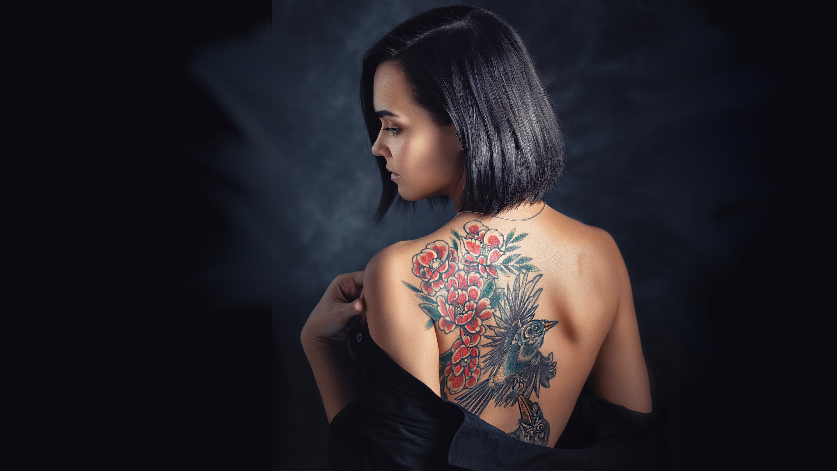 Beautiful dark-haired girl with short hair shows off her tattoo on her back
