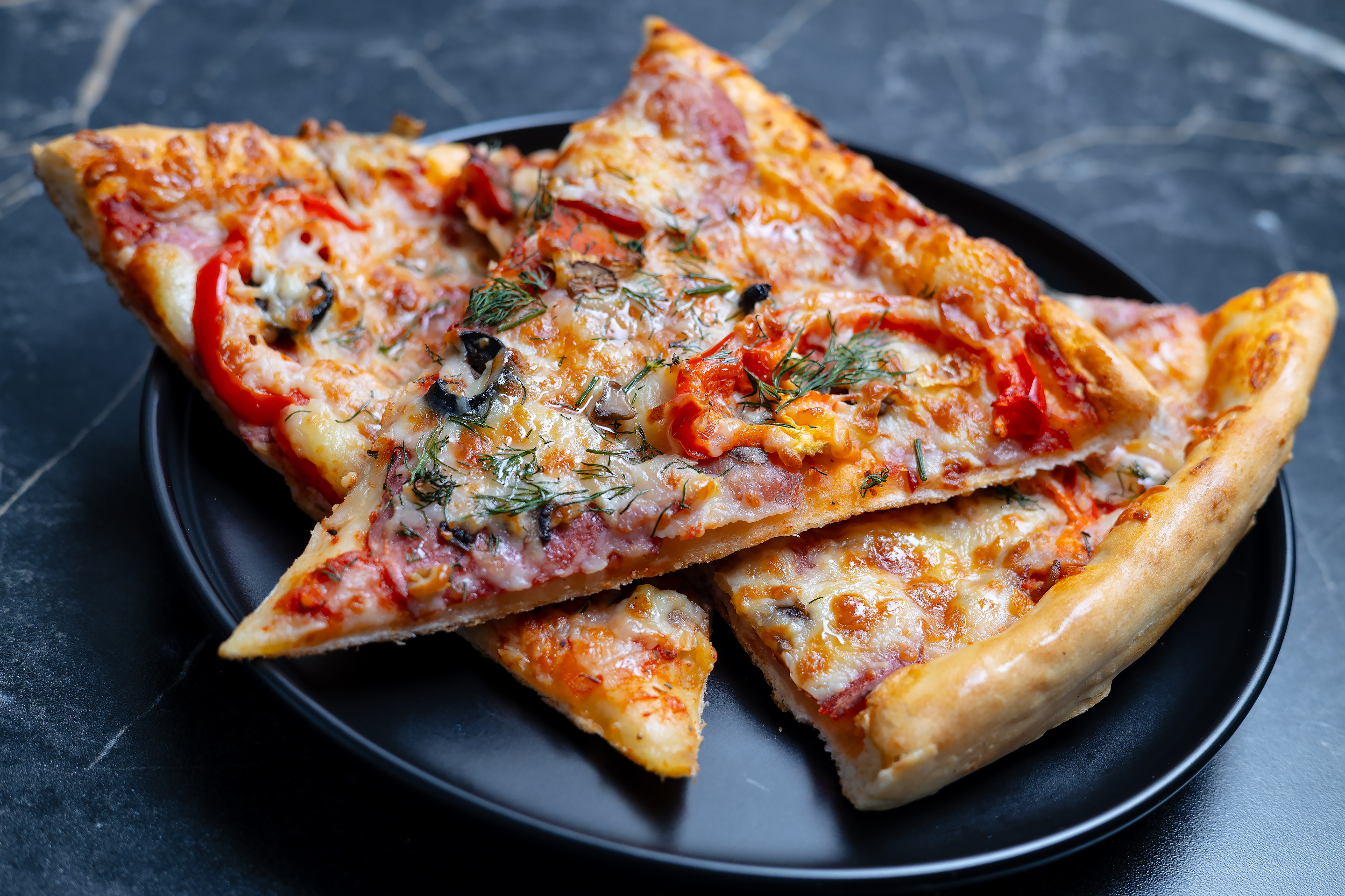 Куски пиццы на чёрной тарелке