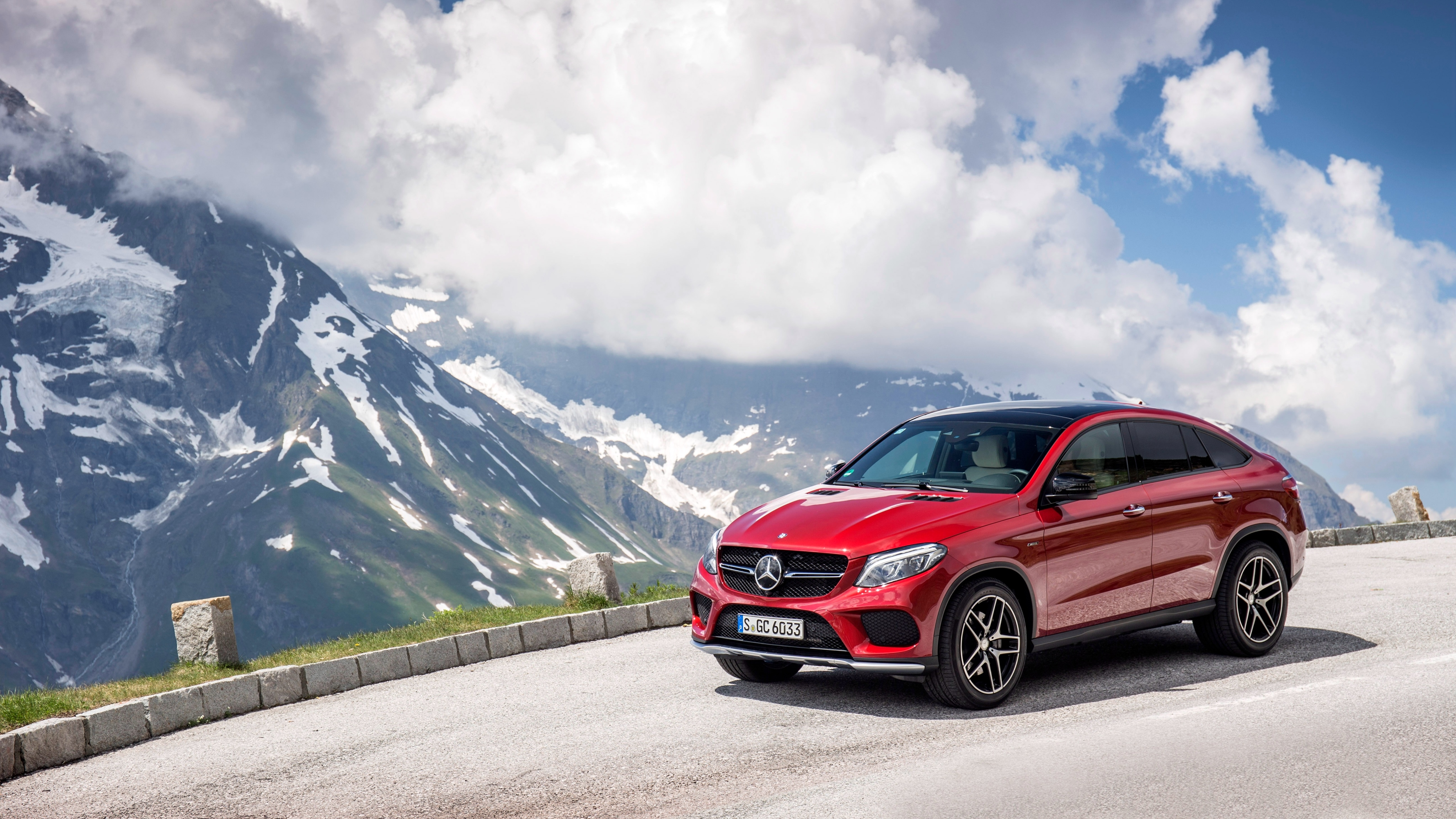 A red Mercedes Benz gle 450 against a backdrop of snowy mountains.