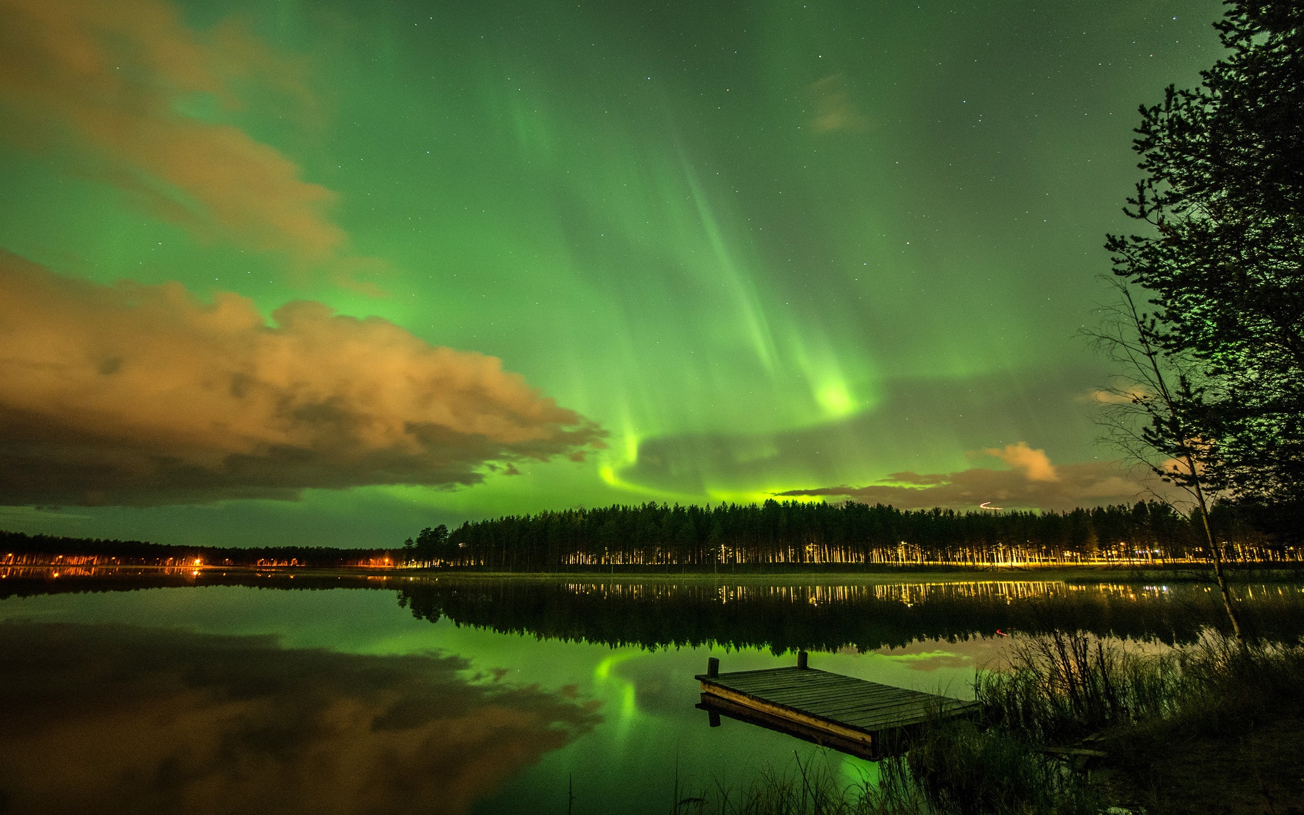 Бесплатное фото Ночное озеро с отражением северного сияния и видом деревьев и деревянного причала вдоль берега.