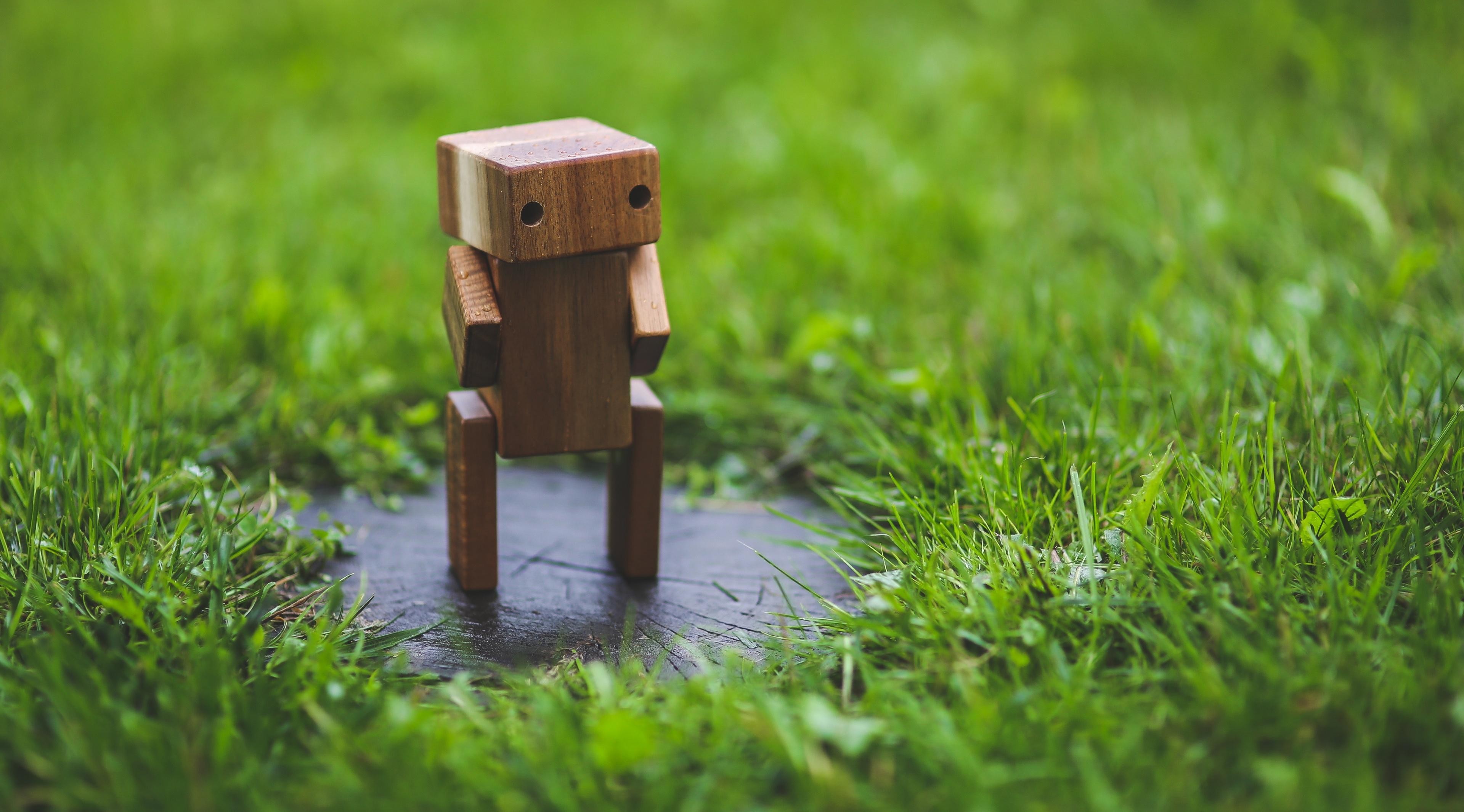 绿色草坪上矗立着一个木制小机器人