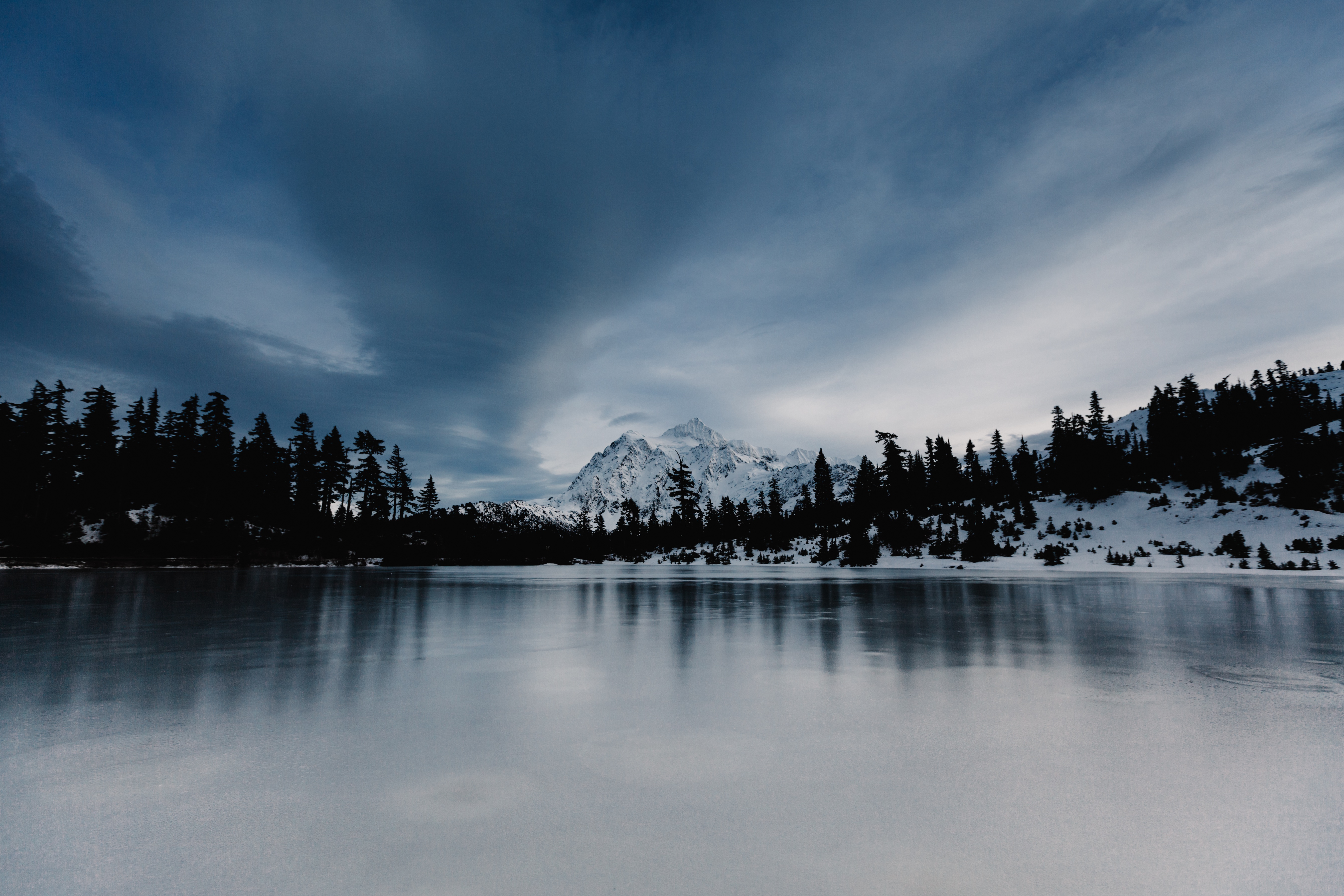 Бесплатное фото Озеро покрытое льдом в лесу с горой