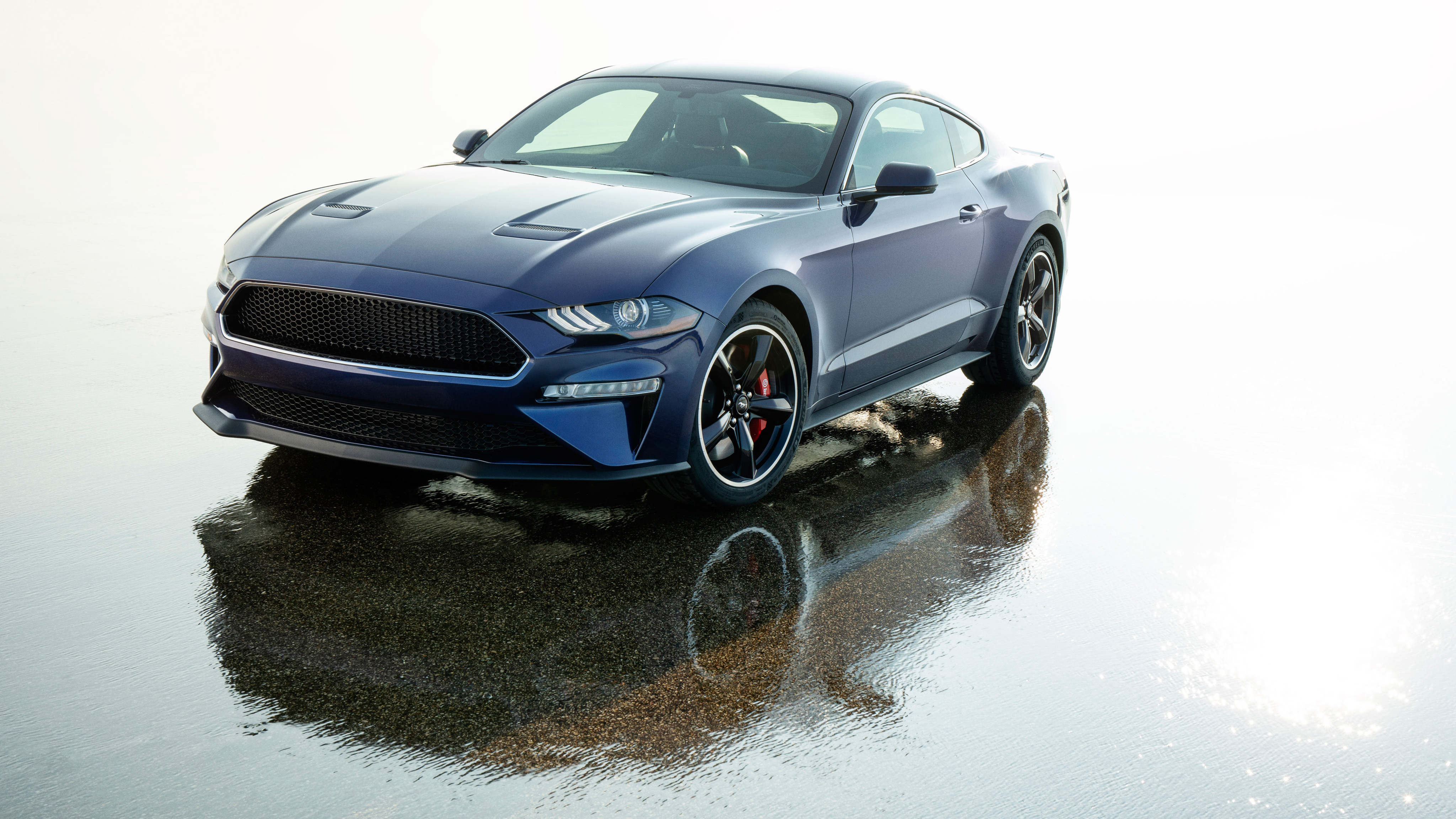 Free photo A blue Ford Mustang reflected in the wet pavement.