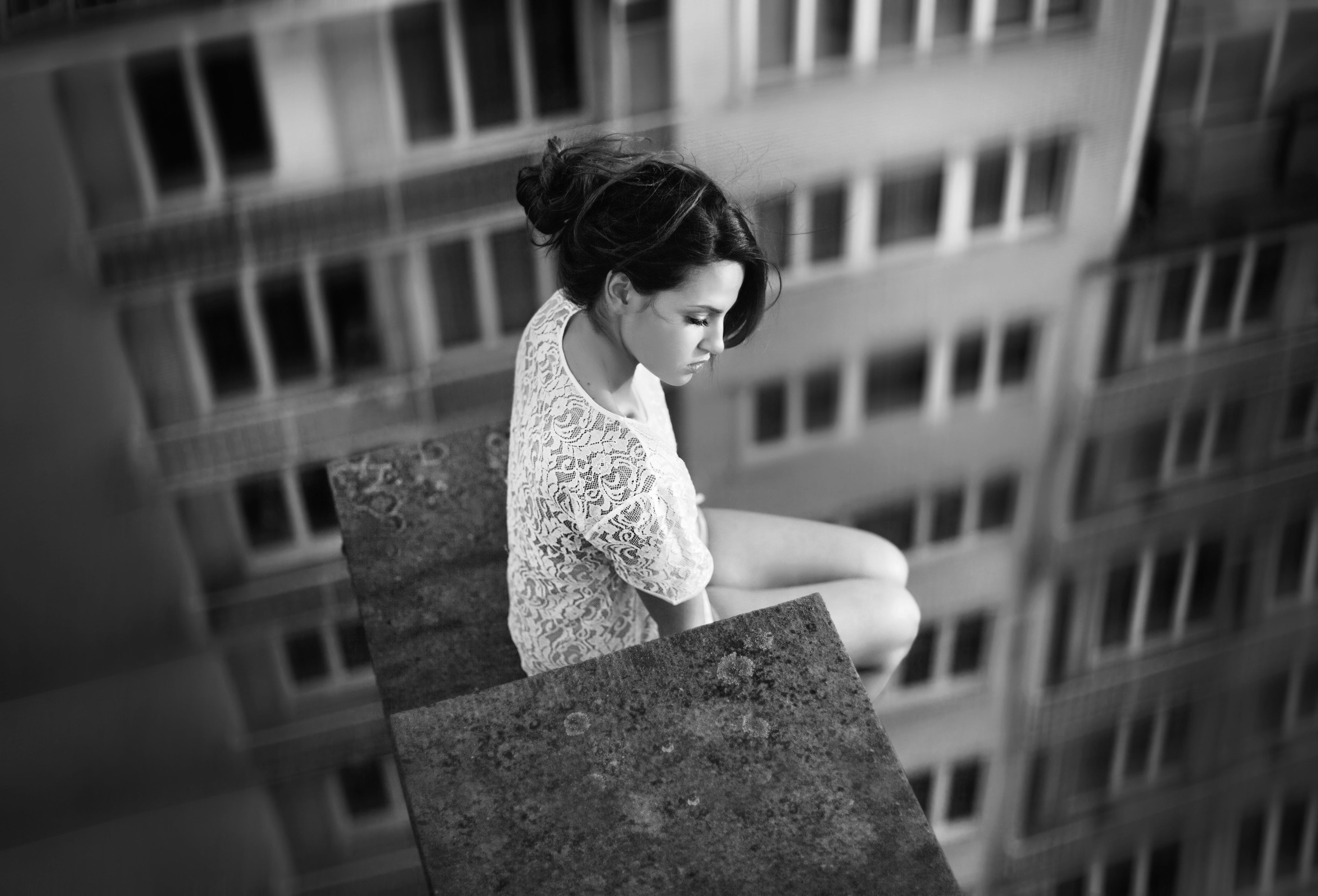 Free photo A girl in a white dress sits on the edge of the roof