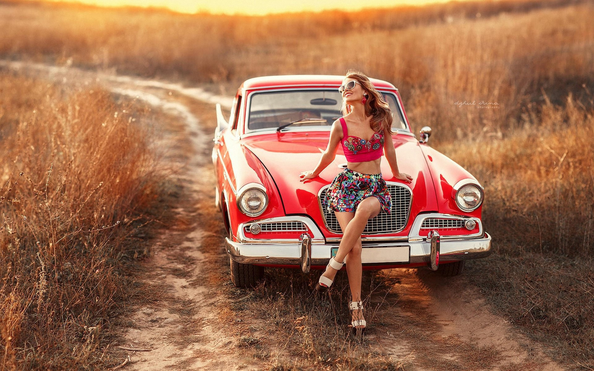 免费照片戴着太阳镜的年轻女孩坐在一辆红色汽车的引擎盖上