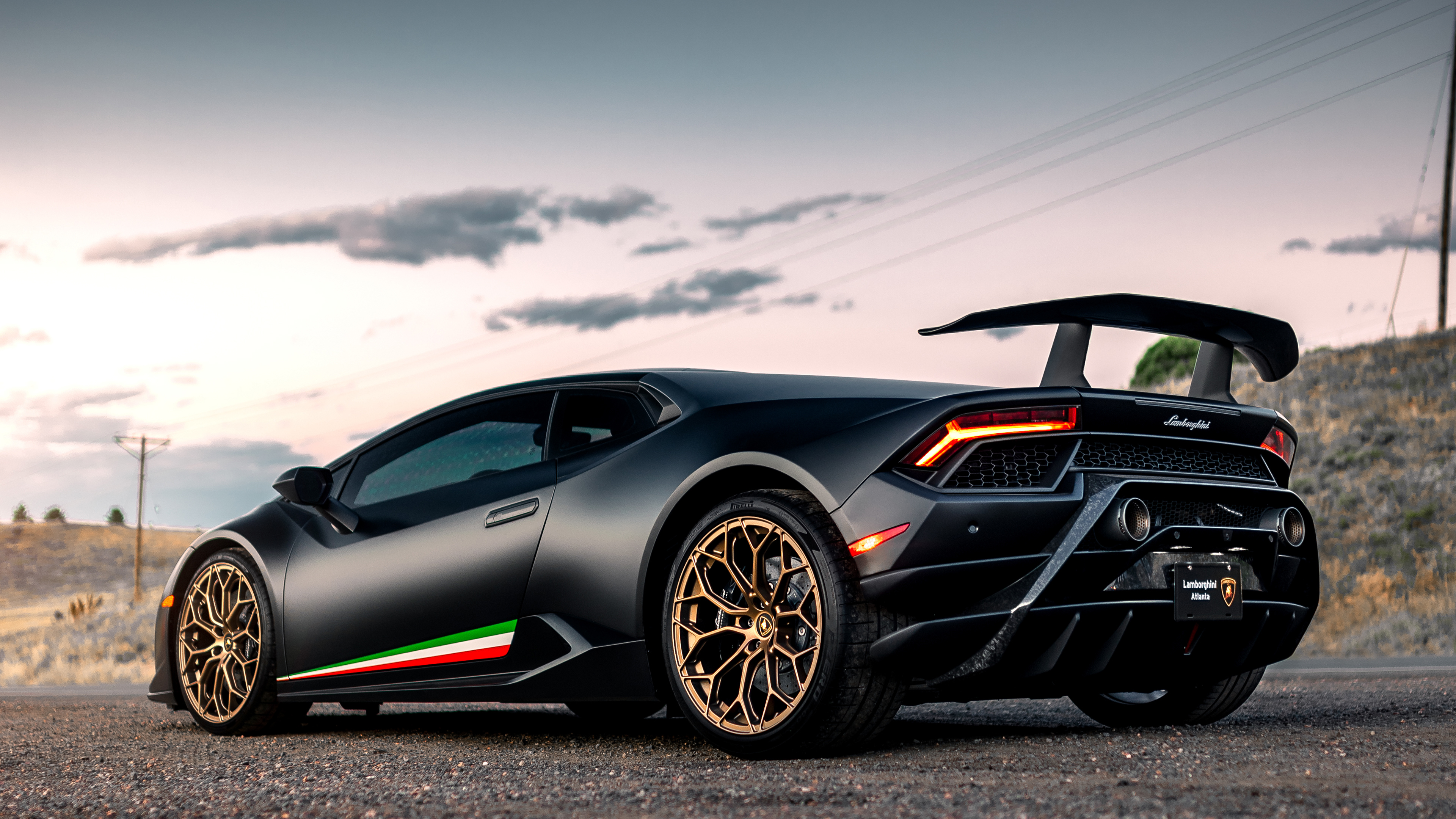 Free photo Black Lamborghini Huracan with gold rims rear view