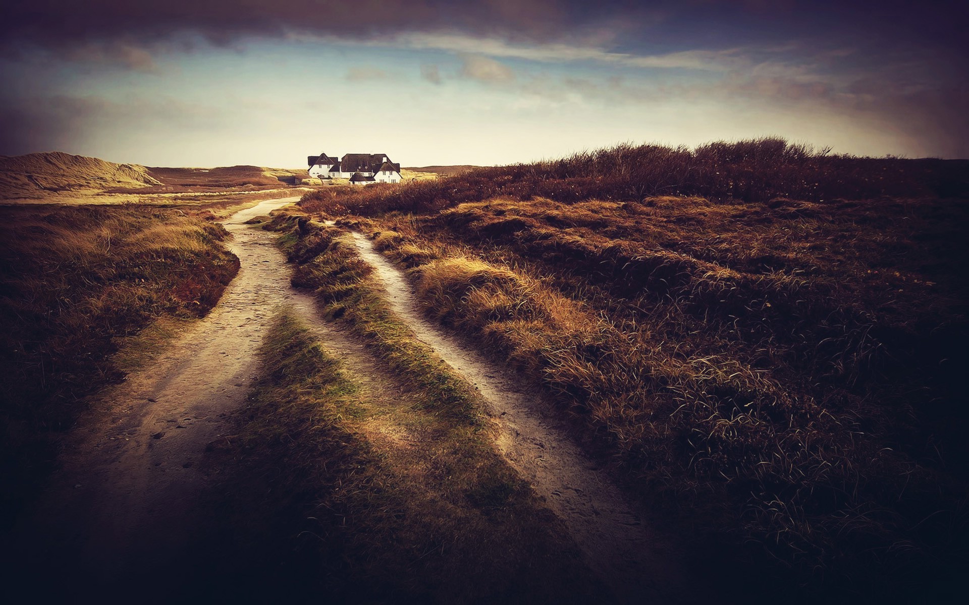 Бесплатное фото Дорога ведёт к дому среди полей под облачным небом, создавая атмосферу спокойствия и уединения.
