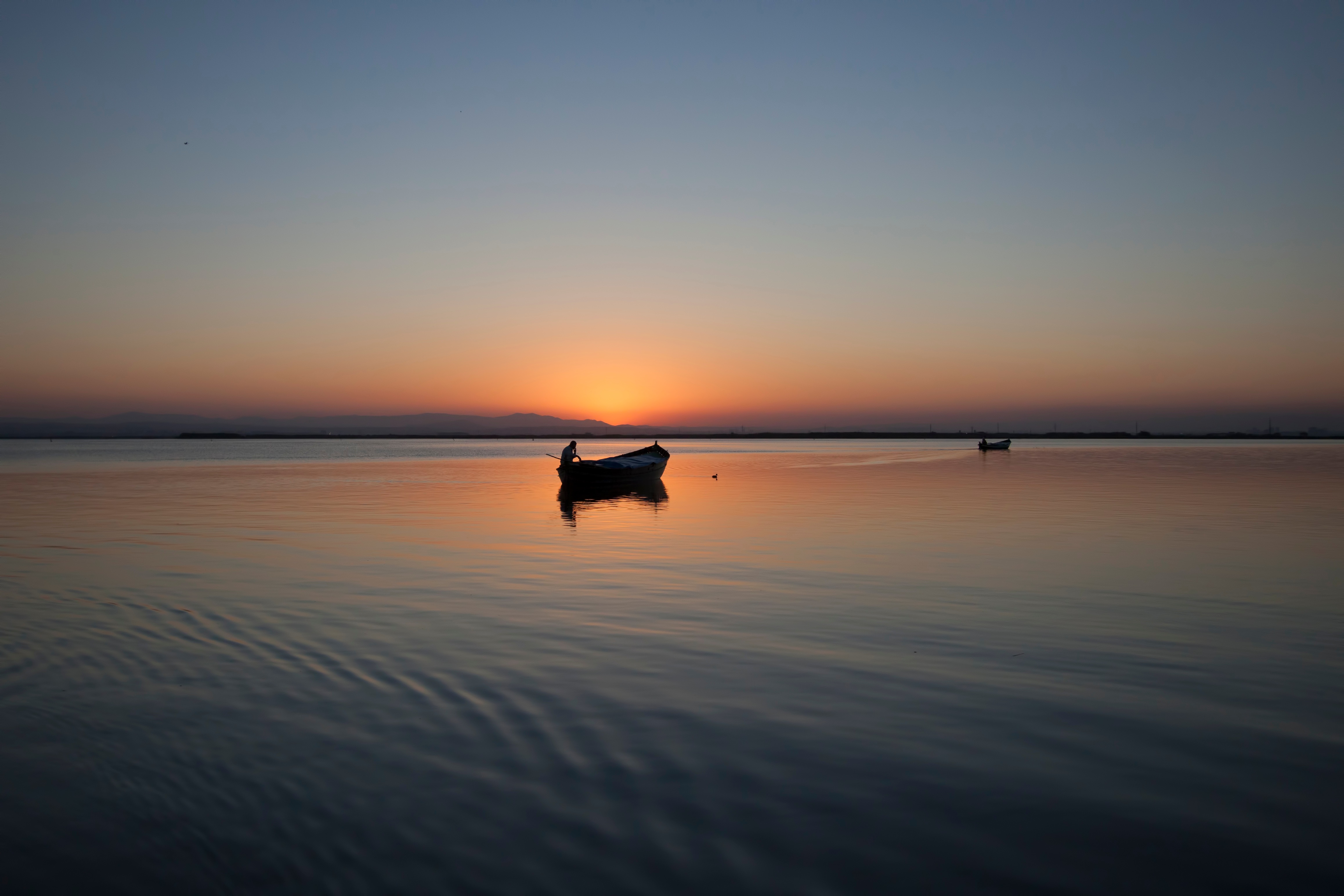 Free photo Silhouette of a boat on the lake during sunset