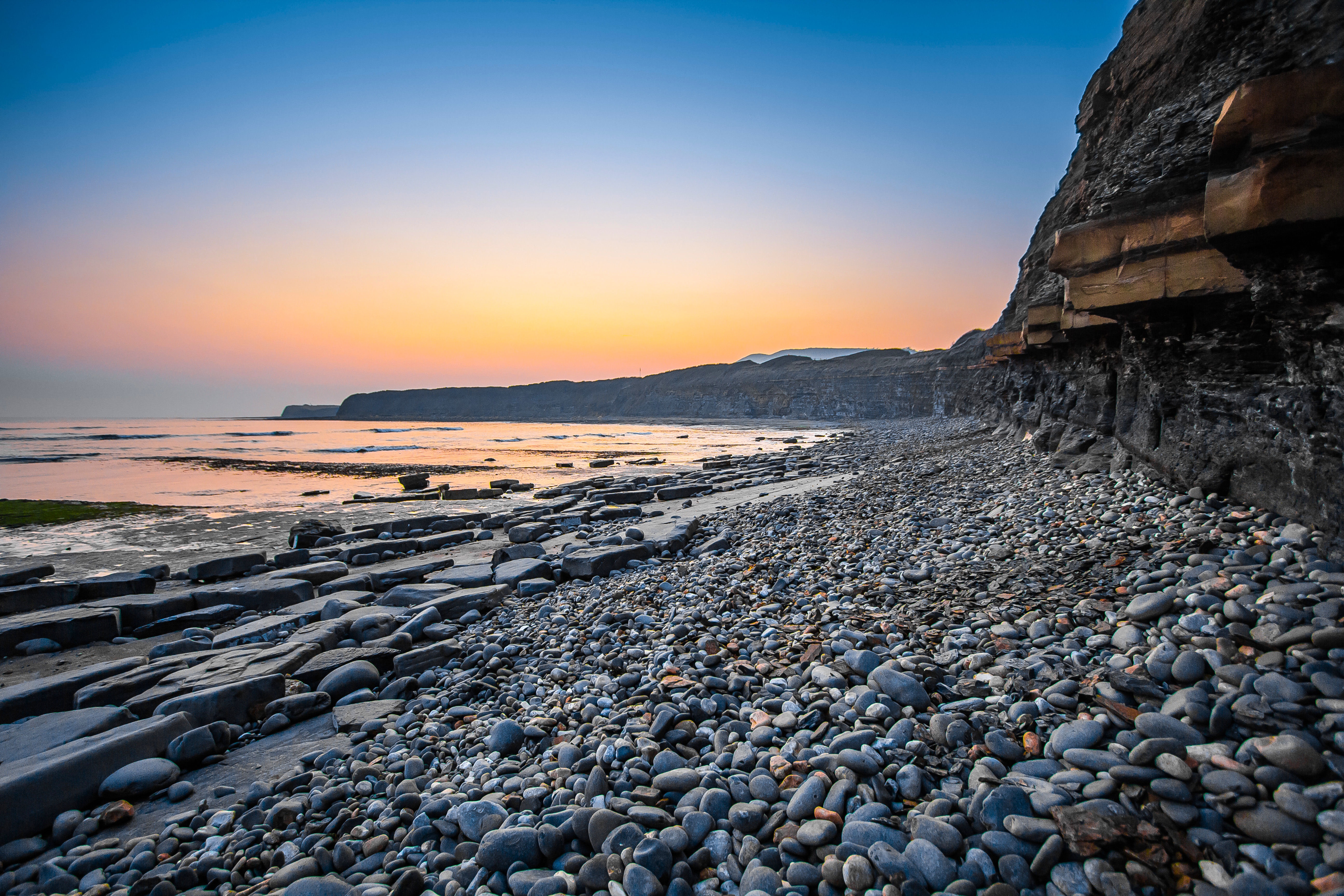 Free photo The sea at the foot of the cliff at sunset