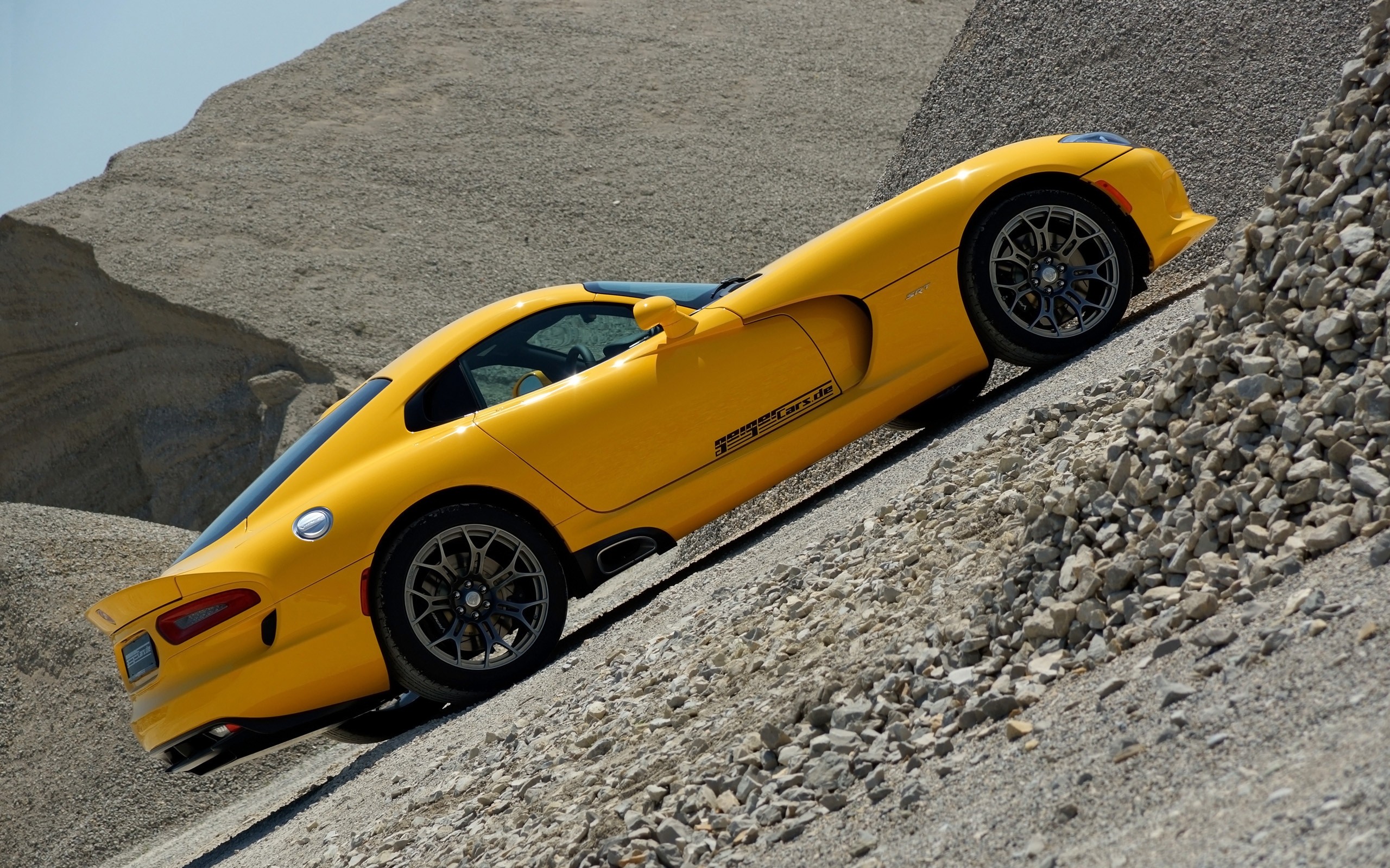 A yellow Dodge Viper in a rock quarry.