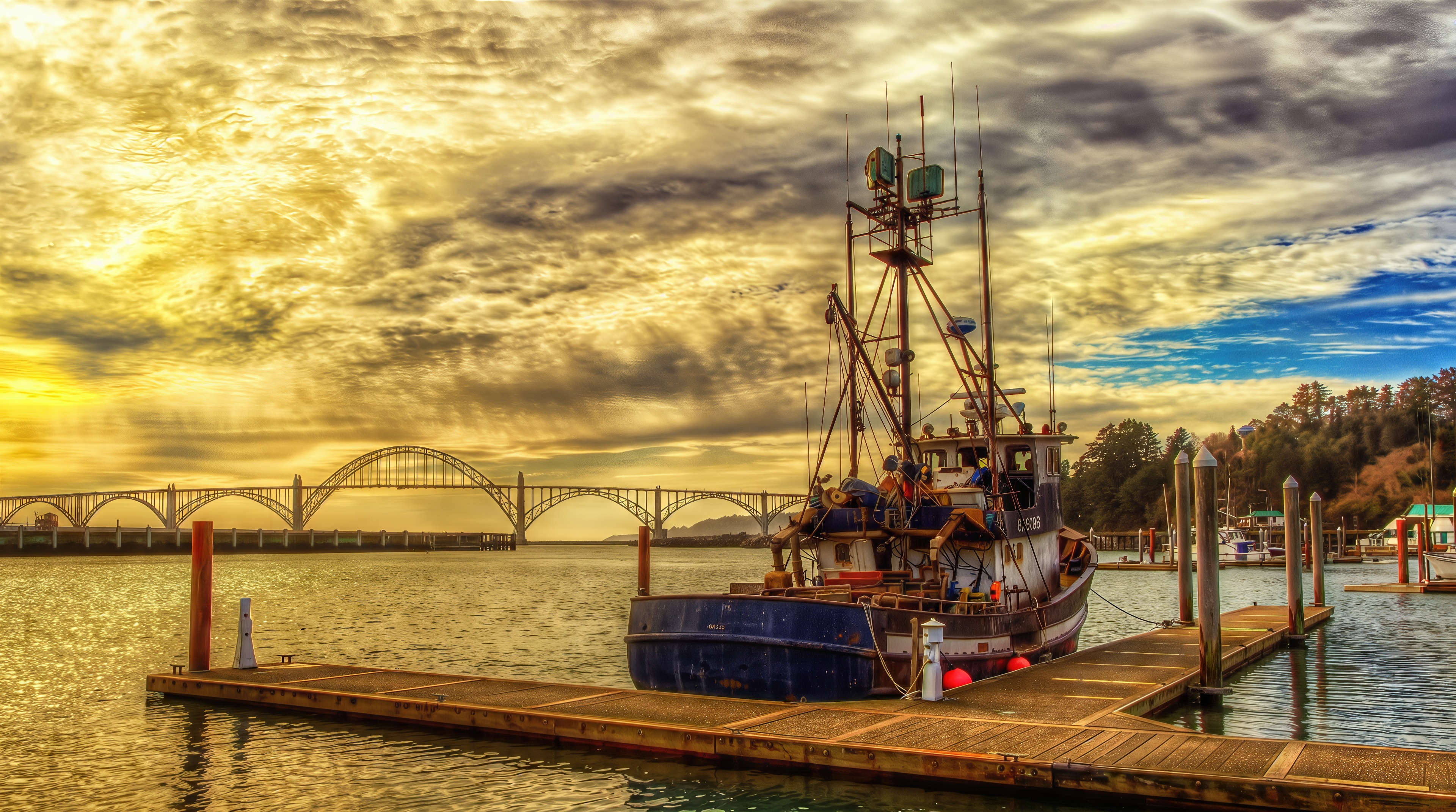 Free photo An old fishing trawler is peacefully moored to a wooden pier in a quiet harbor at sunset.