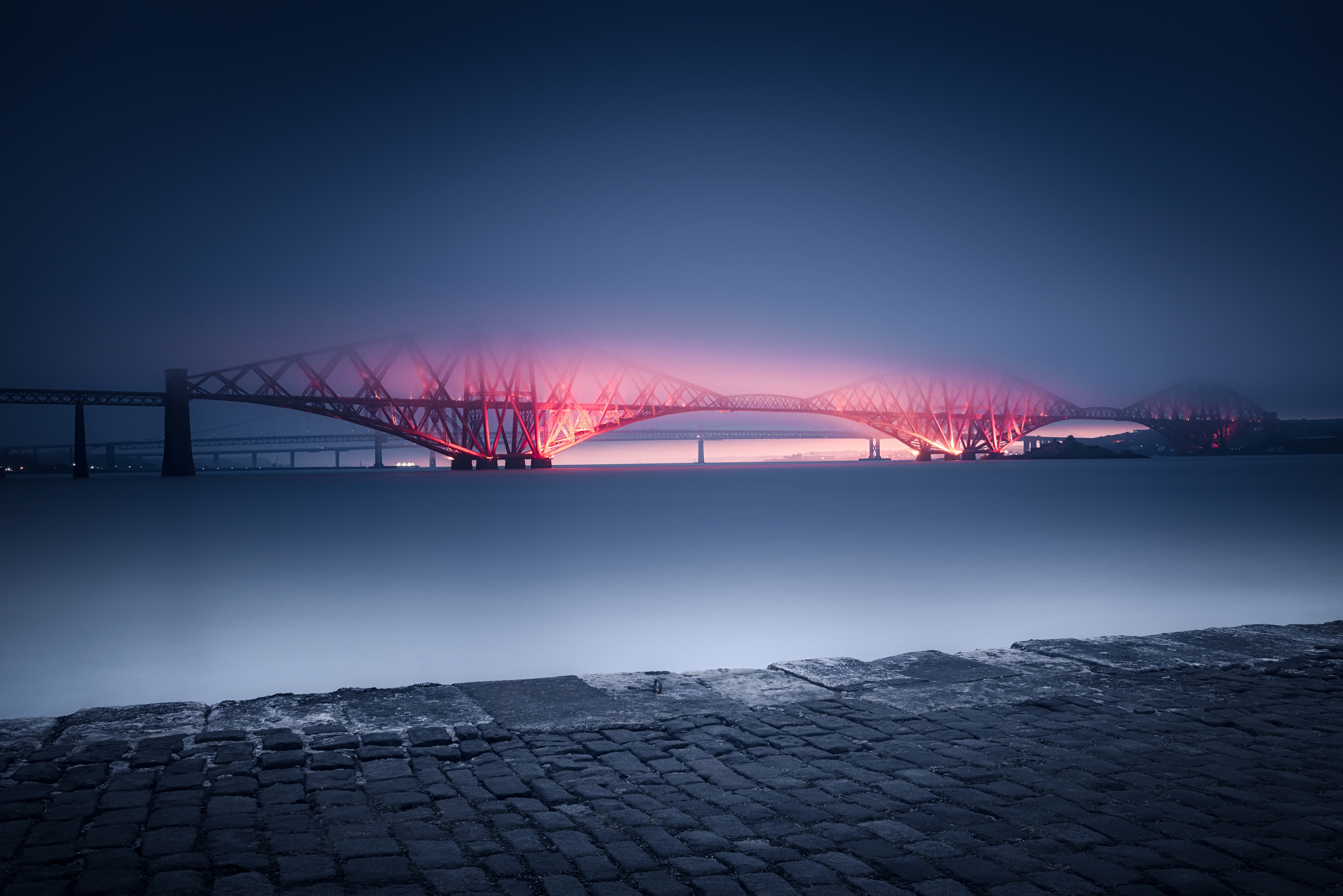 Scottish Bridge is illuminated with red light during sunset in the fog