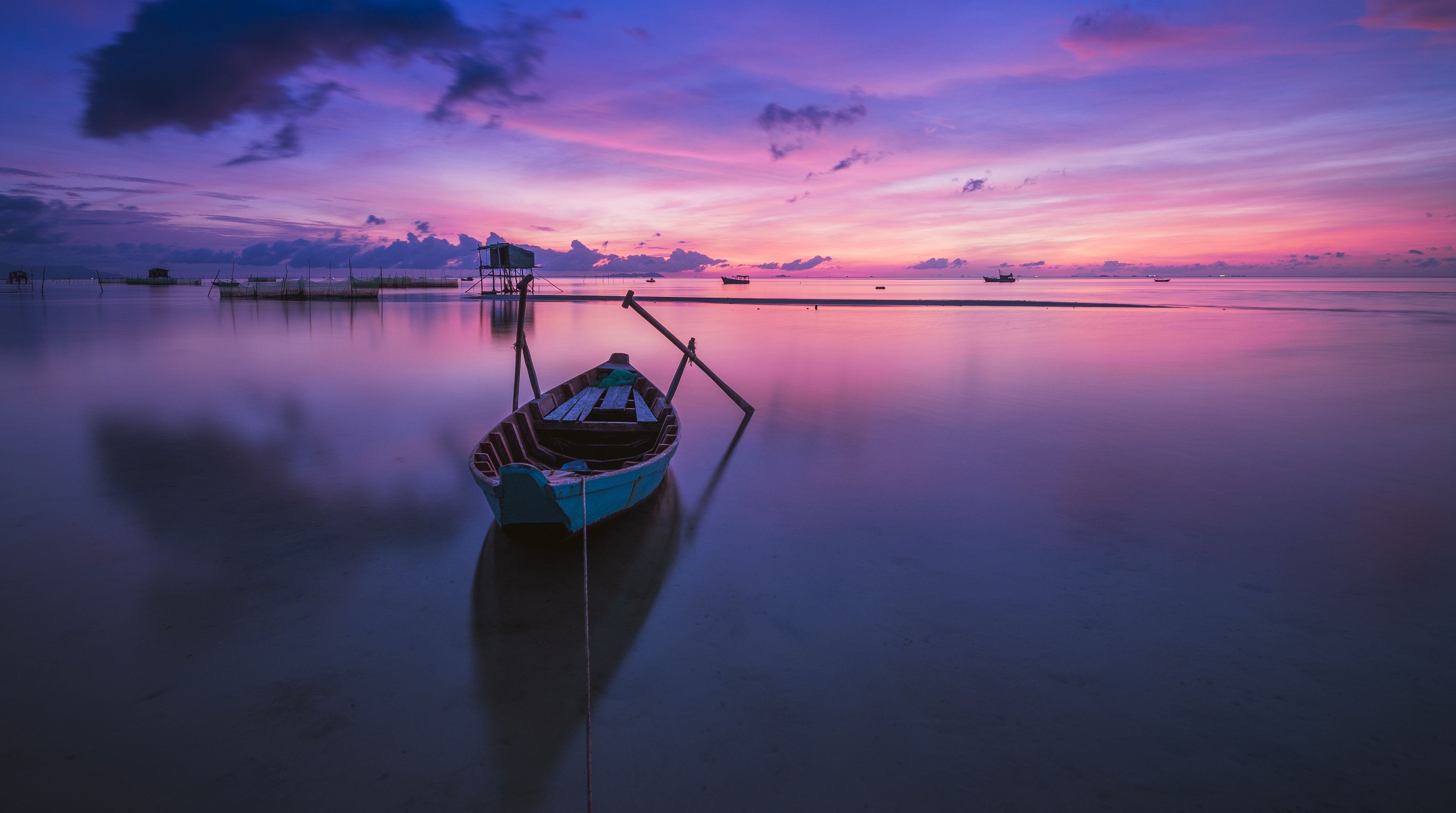 A boat on a lake with a purple sunset