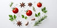 Свежие помидоры, розмарин, петрушка, чеснок и звёздчатый анис на белом фоне.