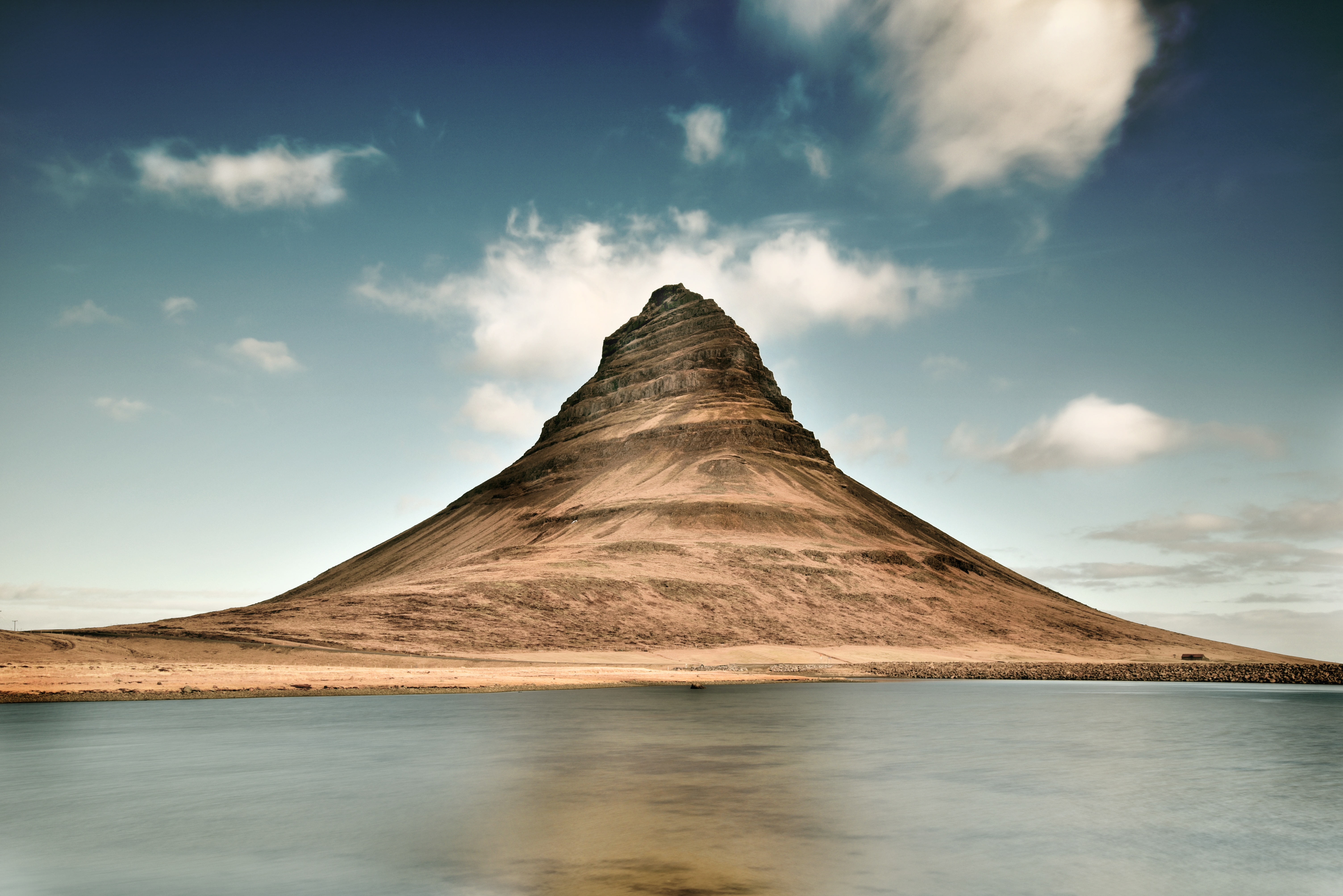 Free photo A strange spiral mountain next to the lake.