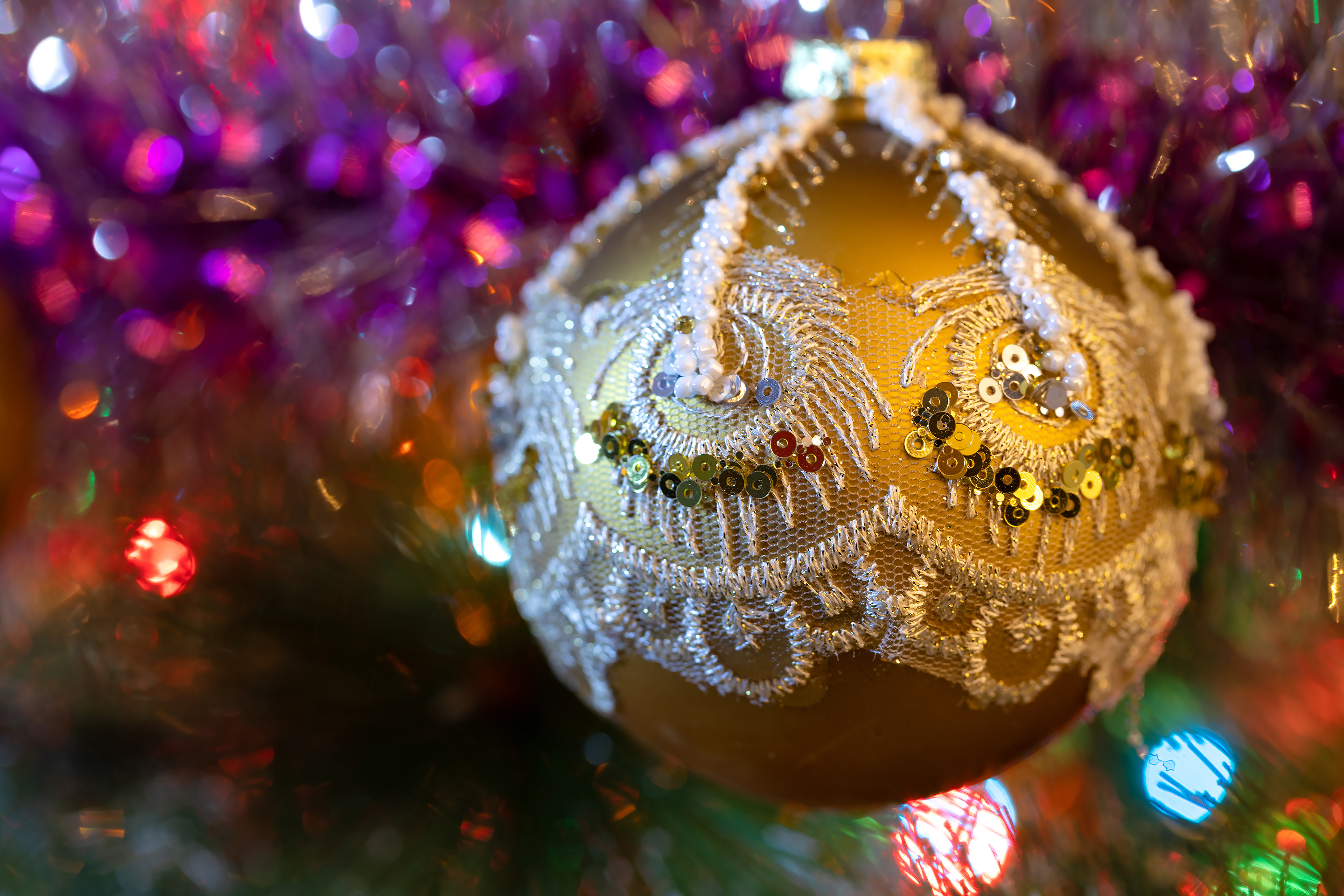 Золотой новогодний шар на фоне блестящей мишуры