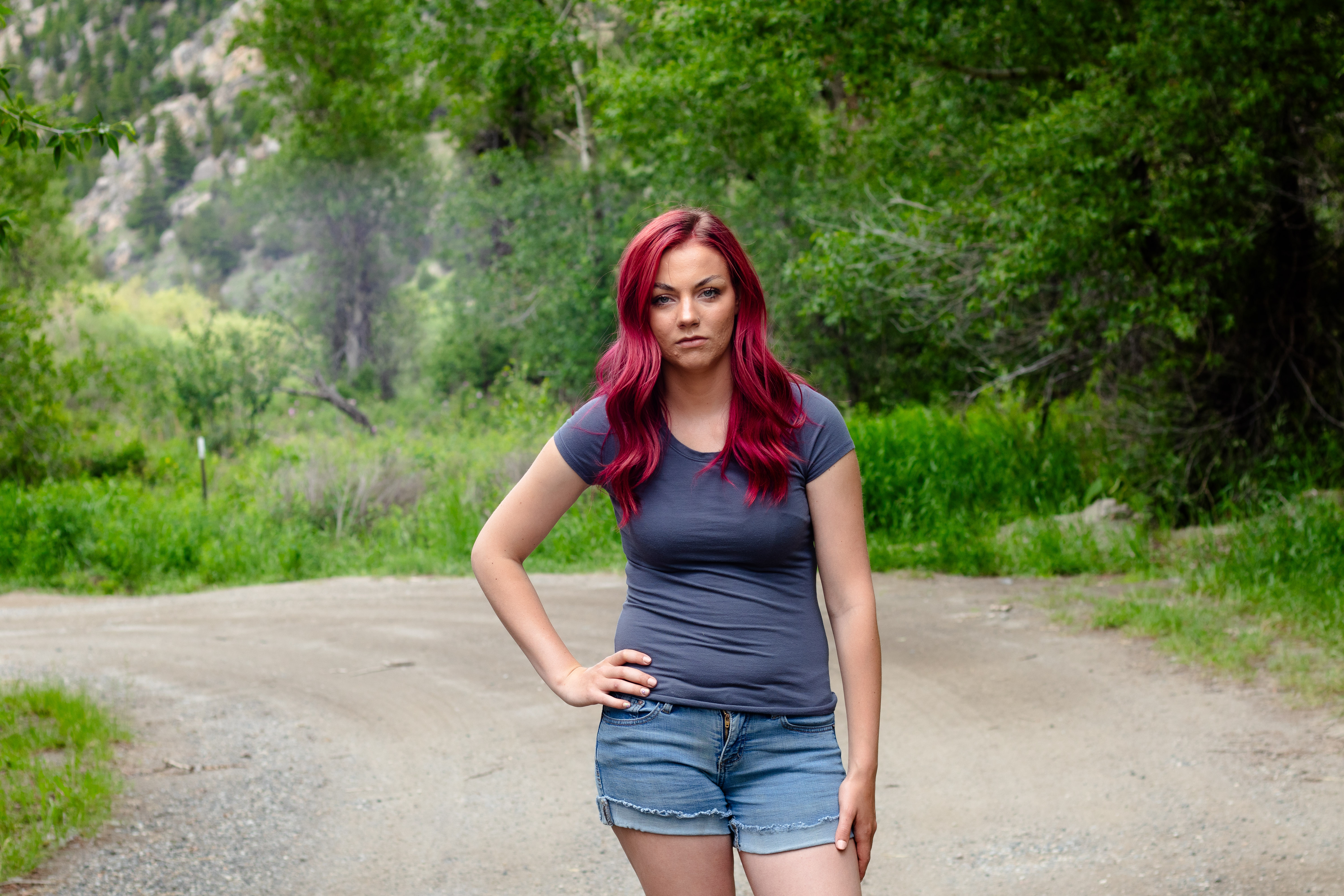 Free photo A girl with pink hair stands on a forest road