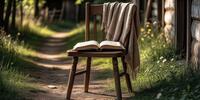 Деревянный стул с пледом и книгой на фоне деревенской тропинки - атмосфера уюта.