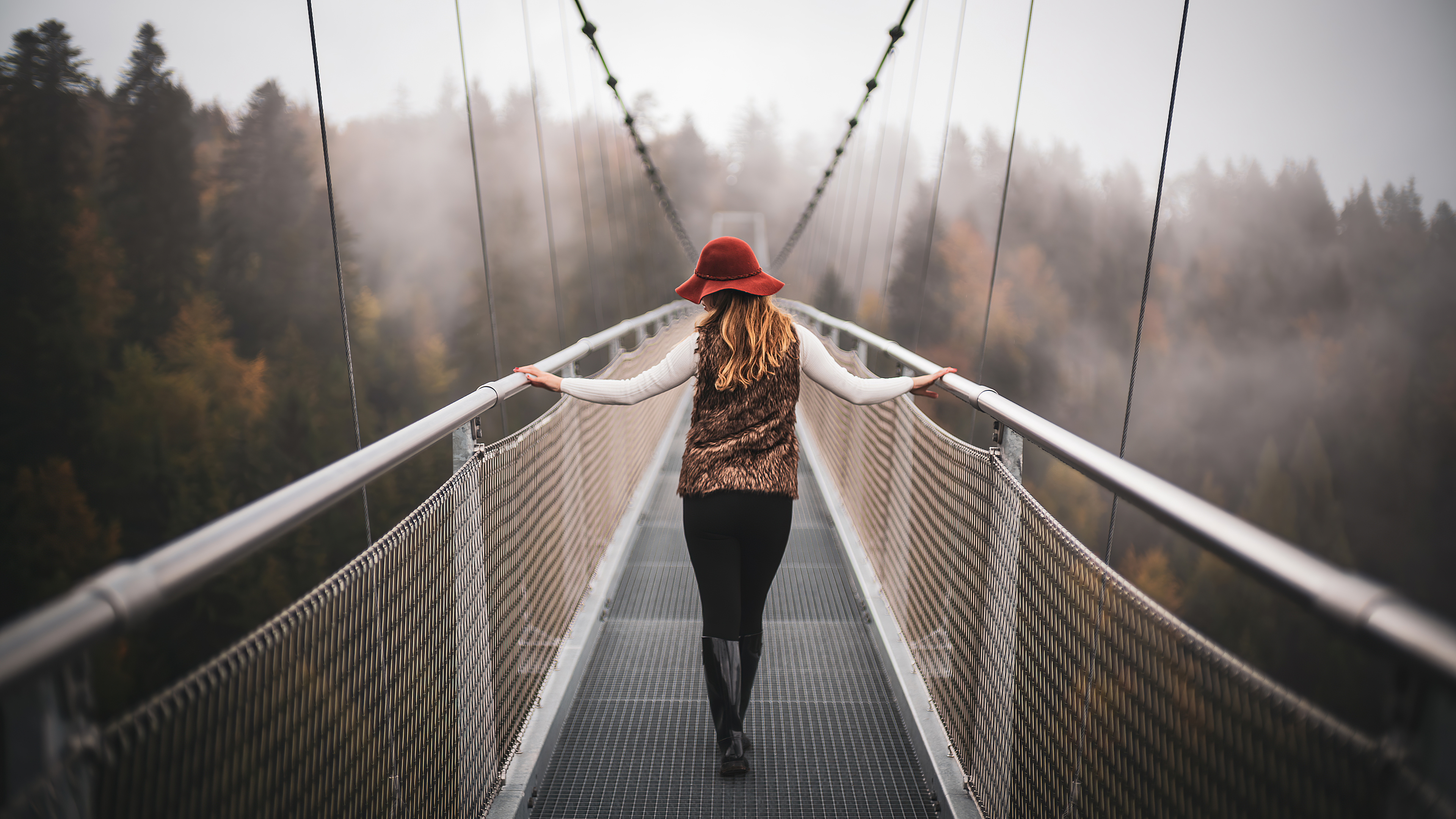 免费照片一个戴帽子的女孩走过一座窄桥