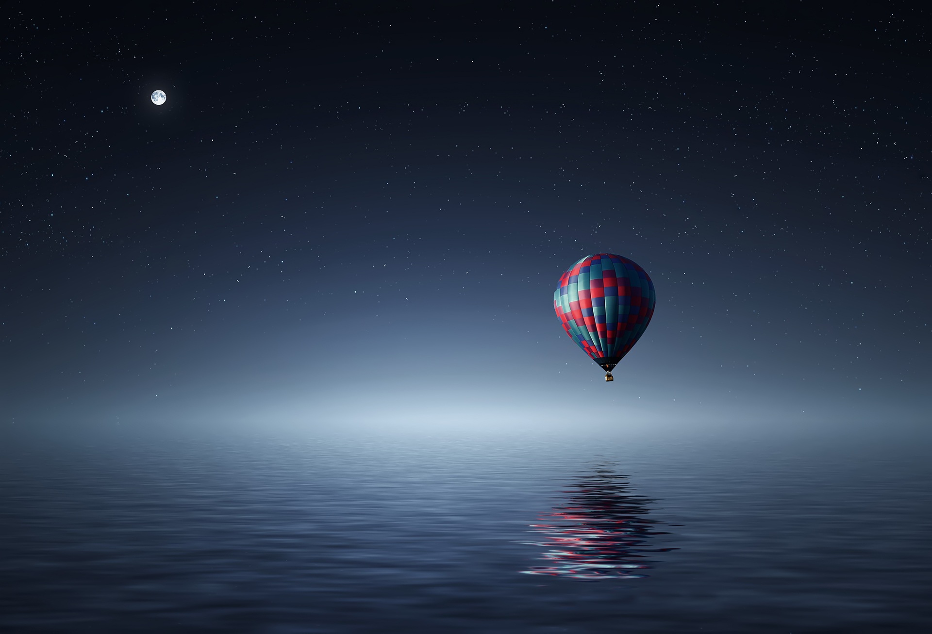 Free photo A lone balloon flies over the ocean at night.