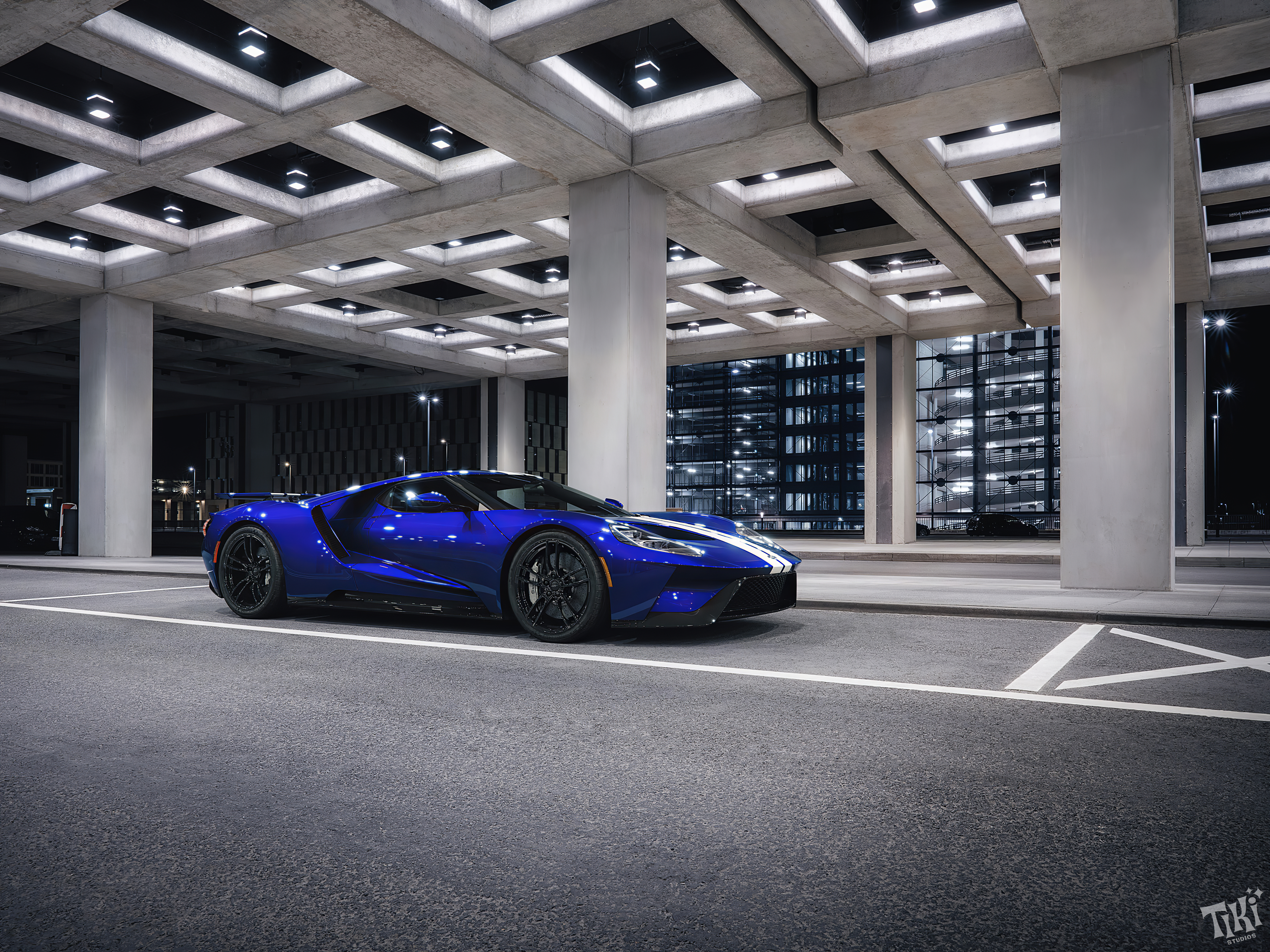 Blue Ford Gt40 with white stripes at night in bright light