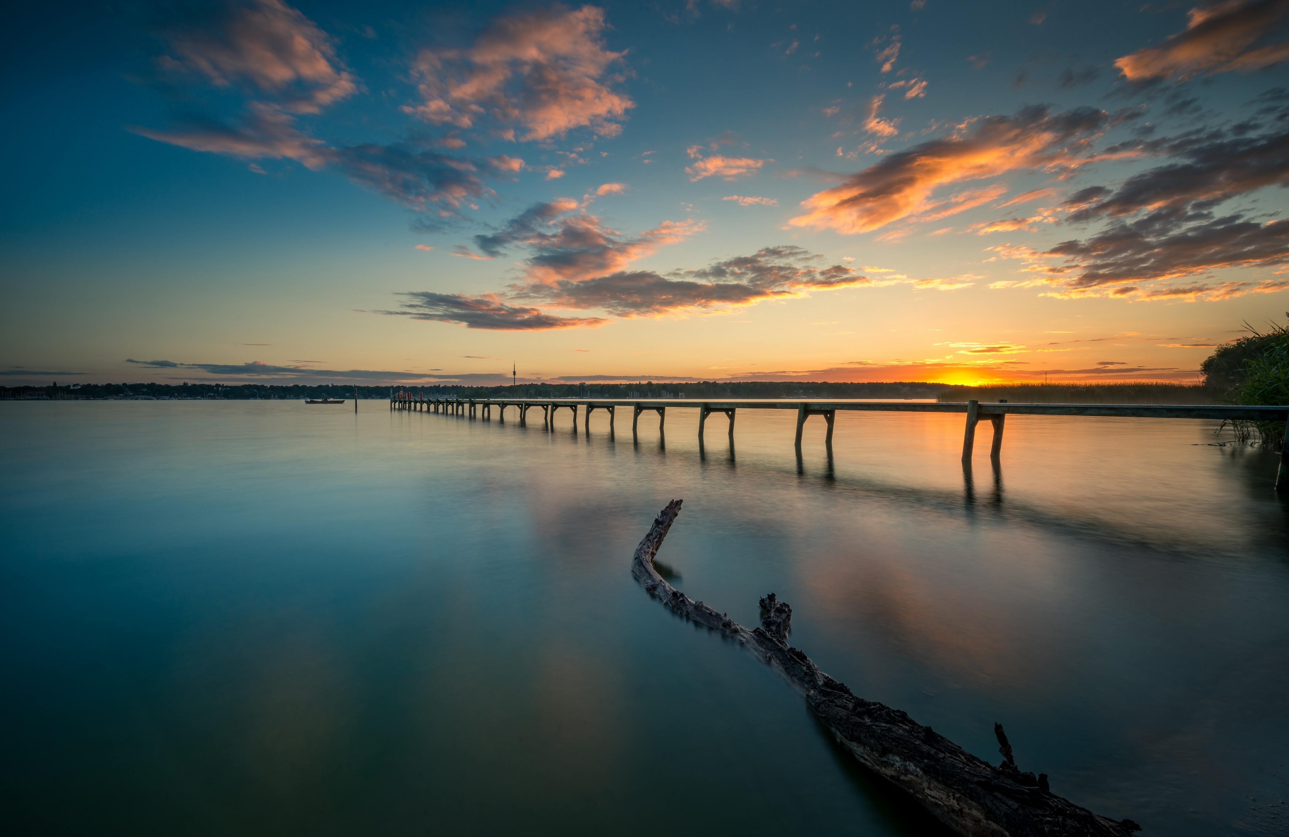 Free photo A long footbridge over the river at sunset