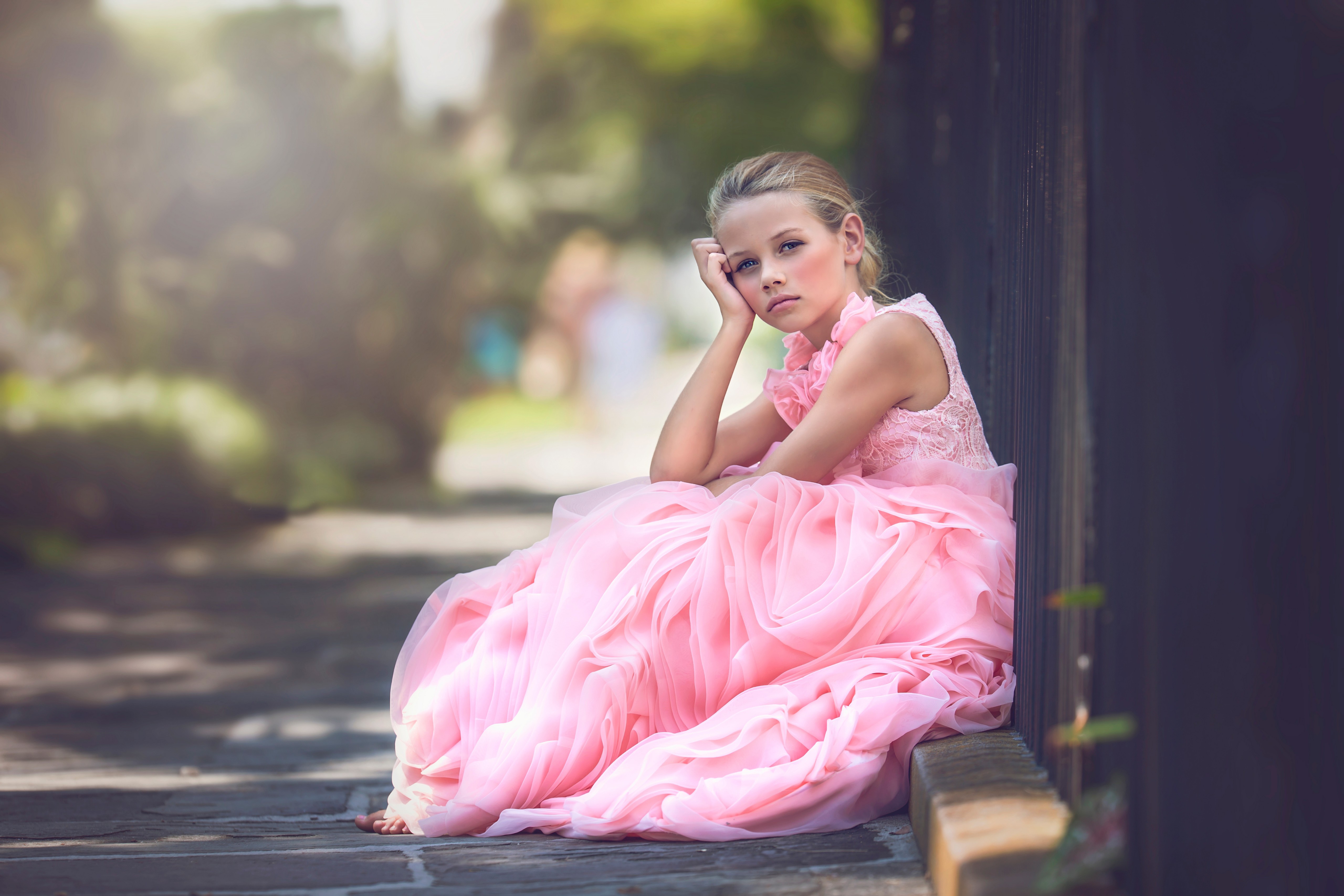 免费照片穿粉色裙子的女孩，坐在篱笆边。
