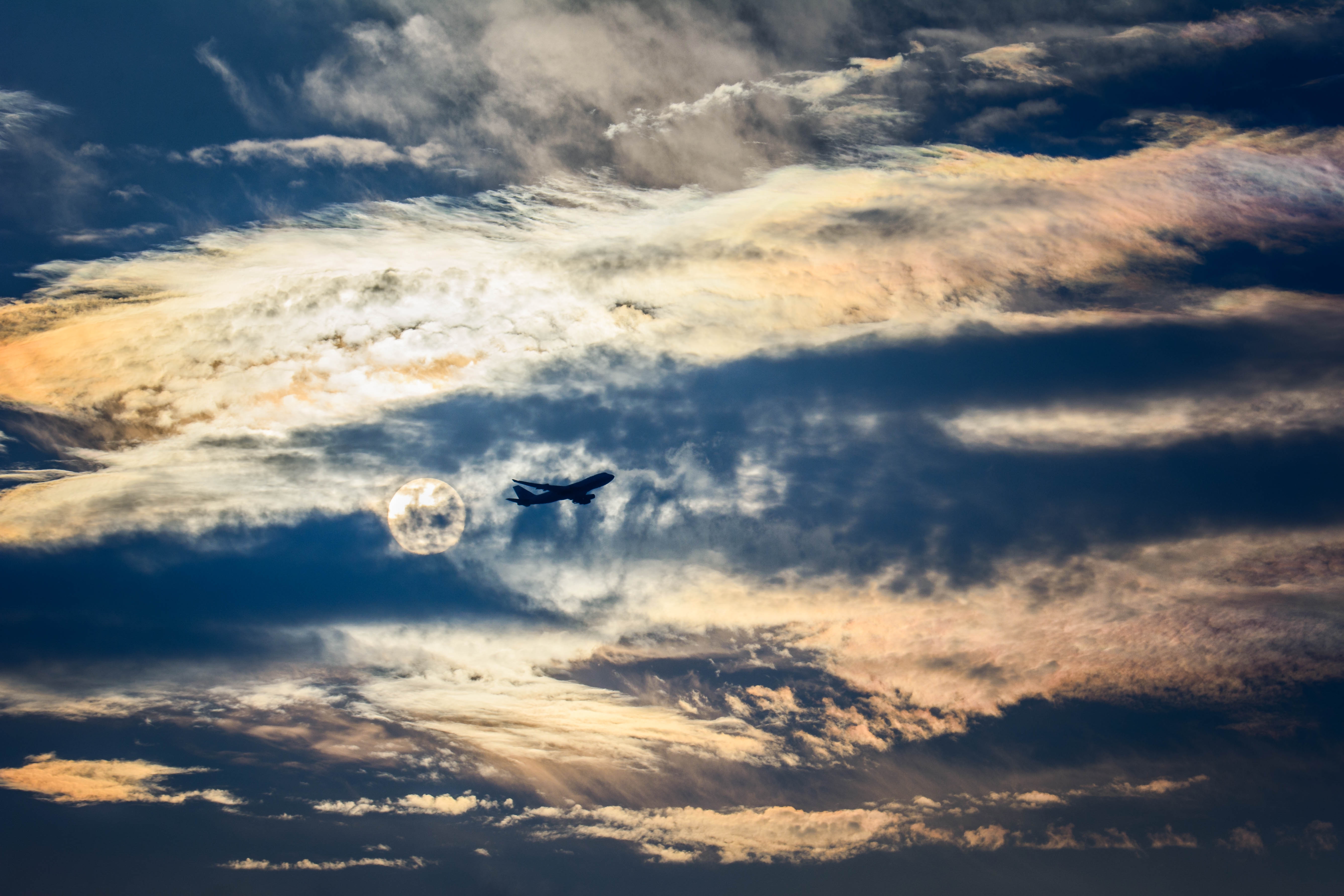 Free photo Aircraft flying over the clouds against the moon