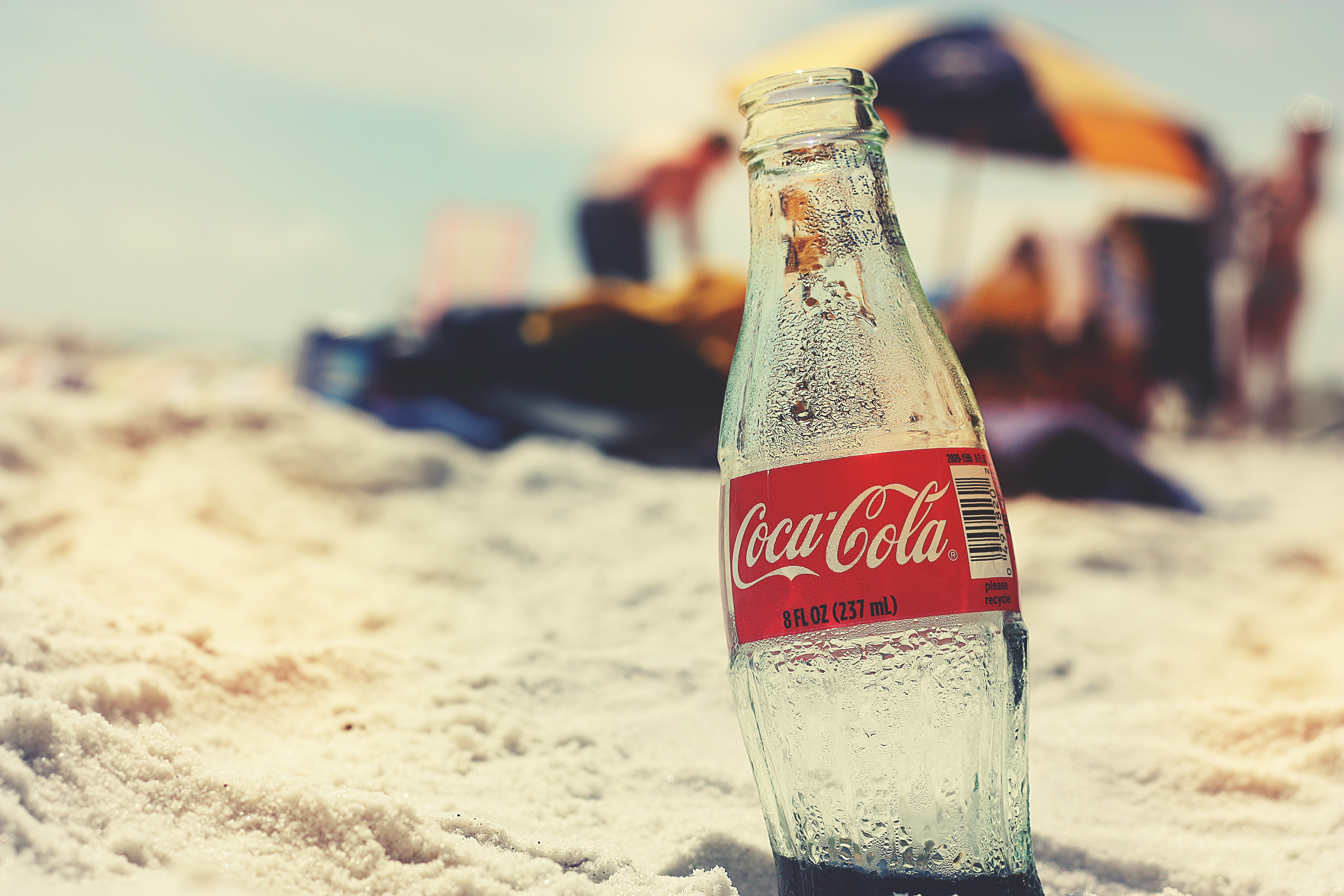 A bottle of cola buried in the sand.