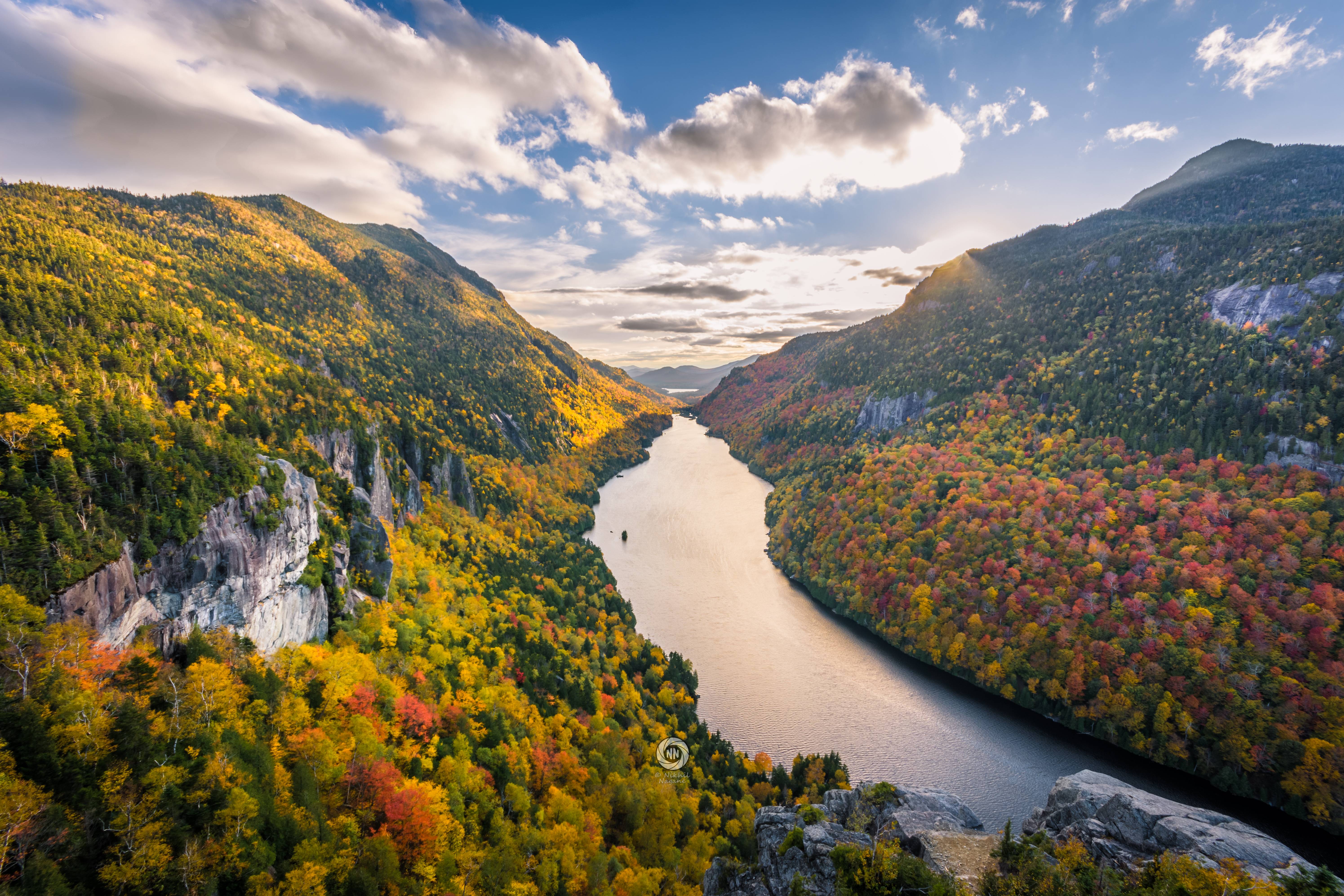 Free photo A river flowing at the foot of the mountains with autumn trees