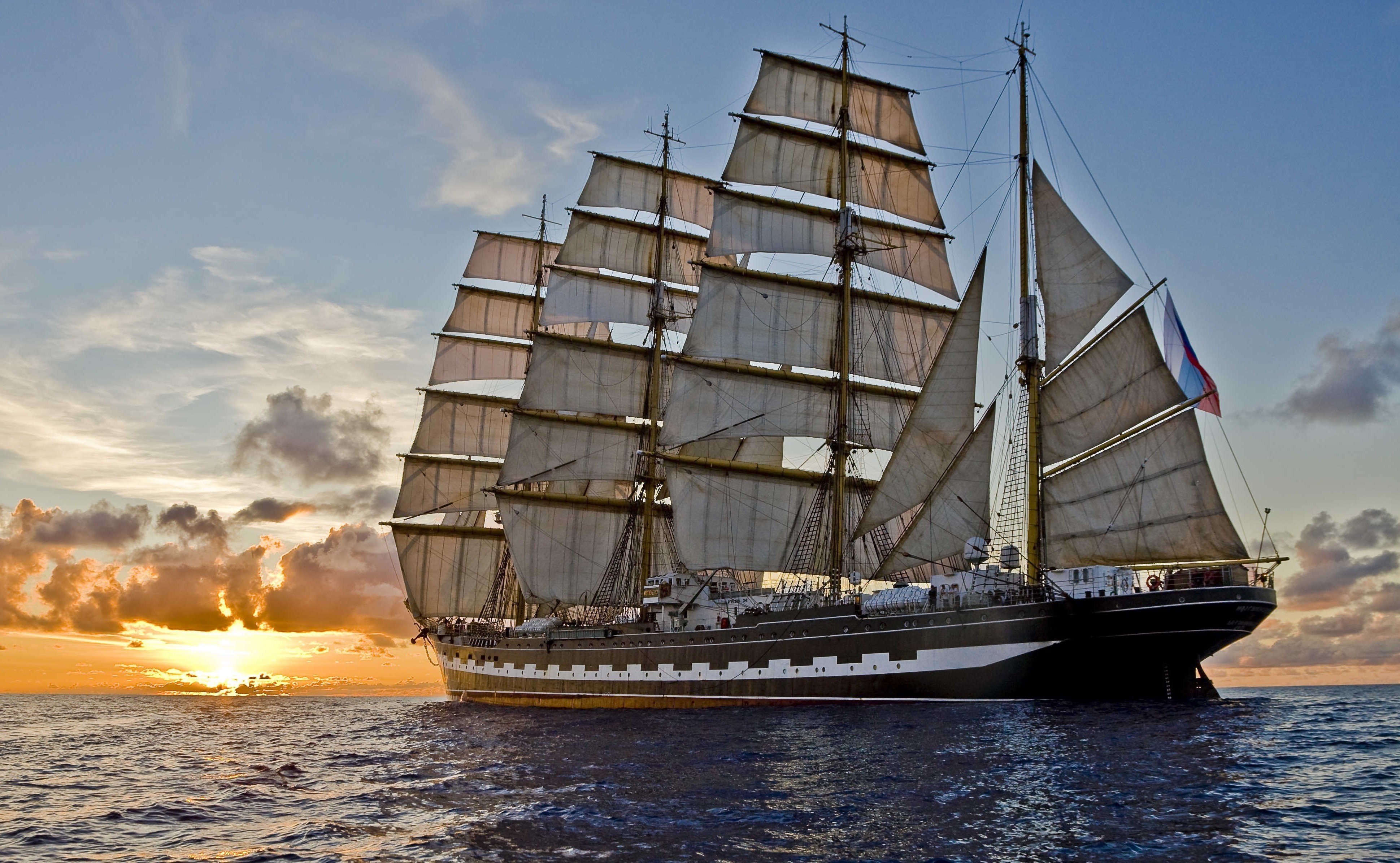免费照片下午，一艘大型帆船在夕阳西下的海面上扬帆起航