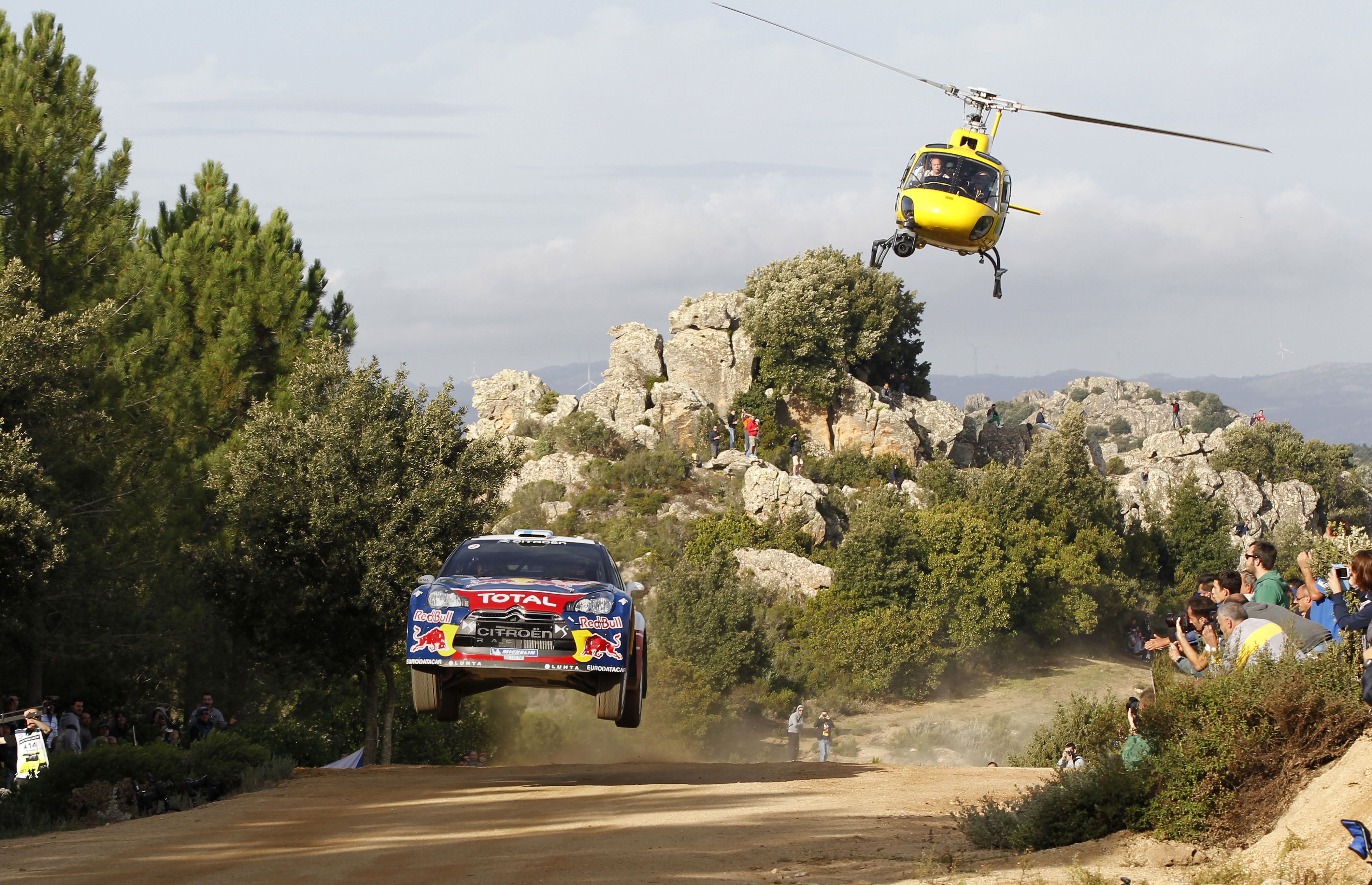 A helicopter chases a sports car at a rally