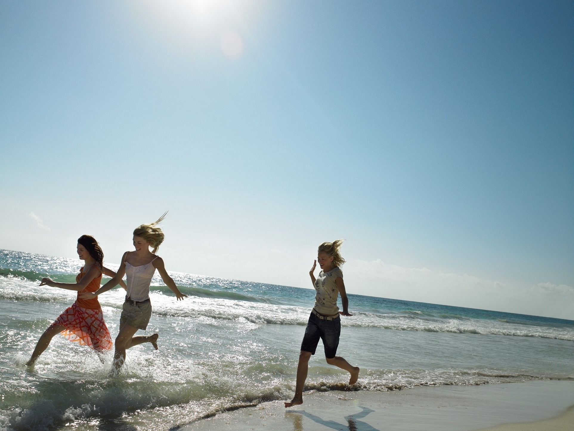 Free photo Three friends are running along the seashore