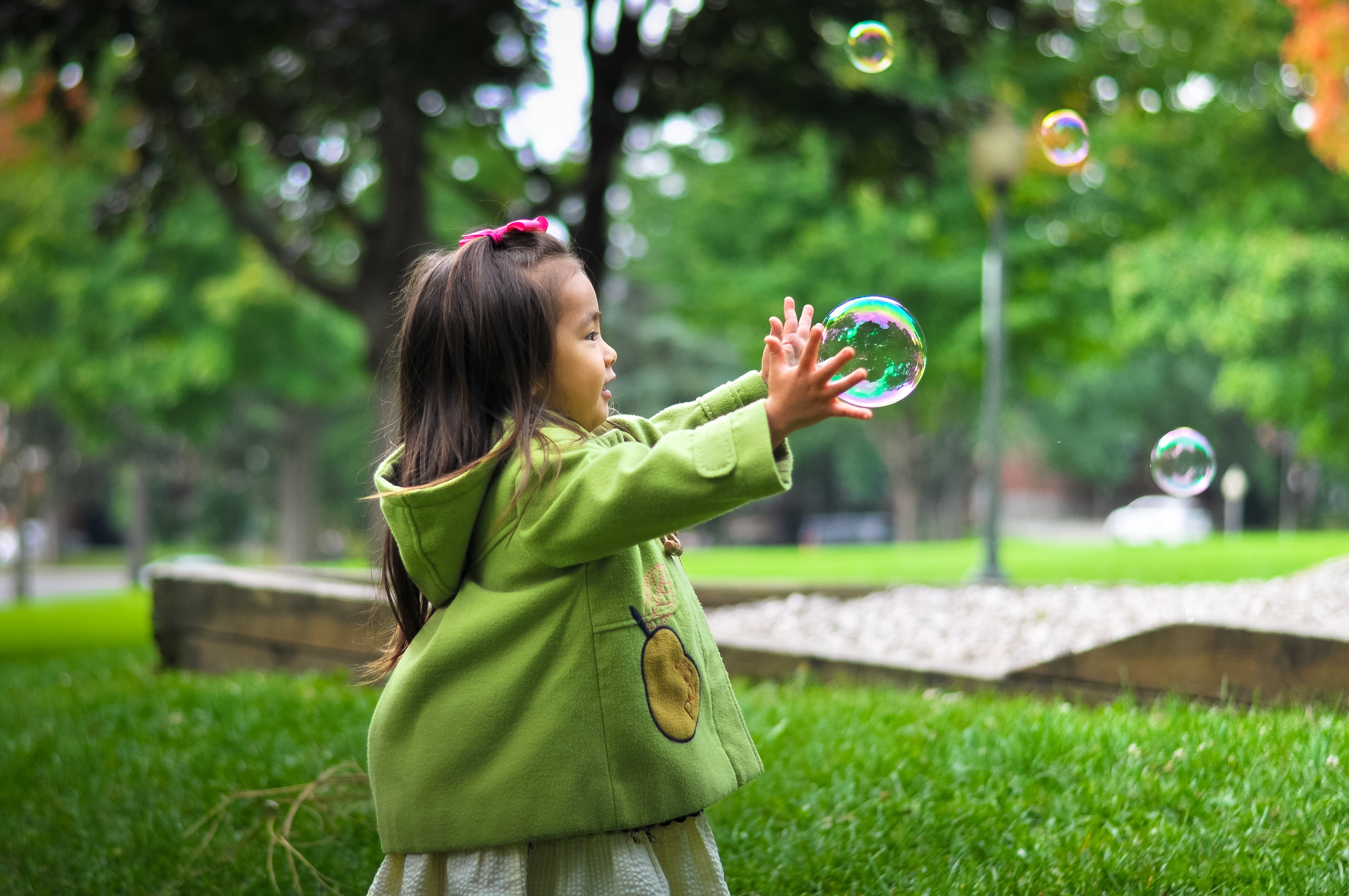 Free photo A little girl playing with soap bubbles.